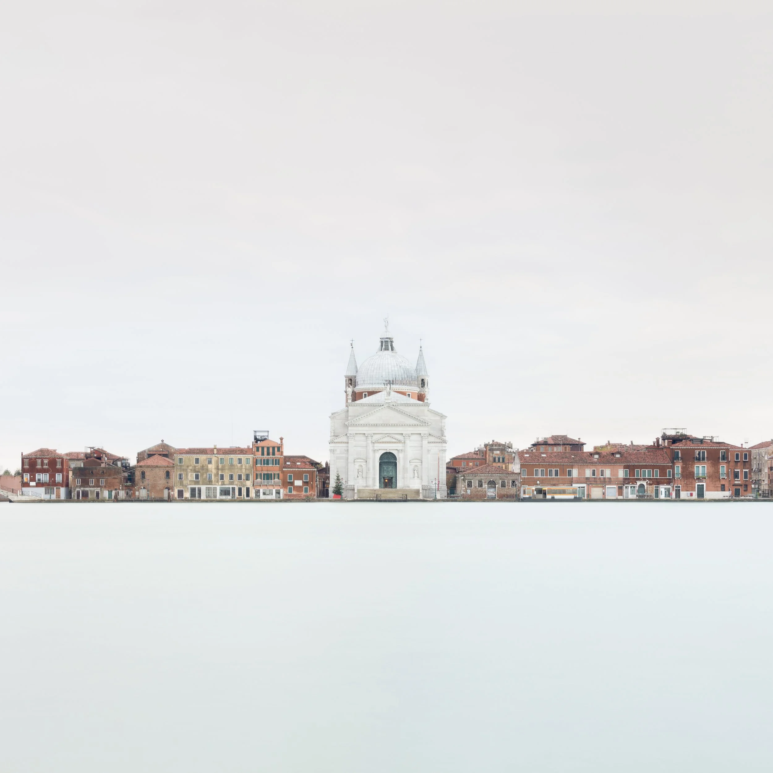 A view of the church of Santa Maria della Salute across the Venetian waterfront, with a pale, overcast sky.