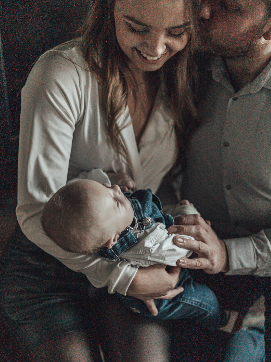 Une famille avec un bébé, une femme et un homme, enroulés dans une étreinte tendre, partage un moment intime et heureux.