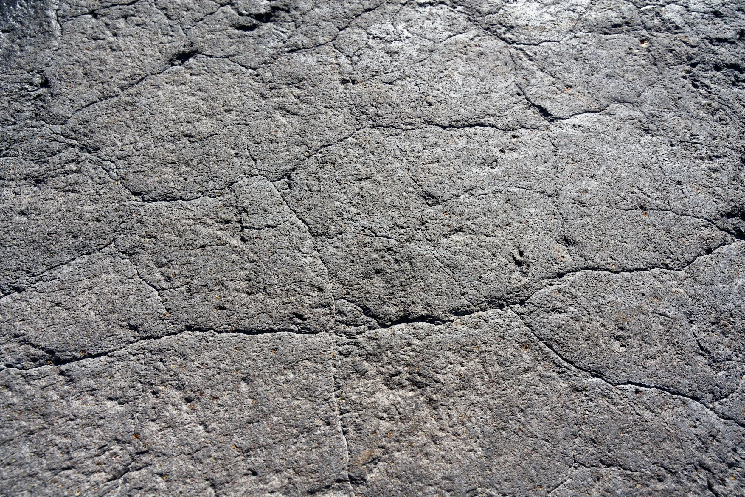 close-up of a cracked concrete surface with various cracks and a rough texture.
