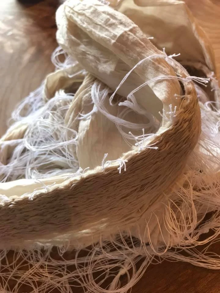 Close-up of a nui stitched shibori, ready to dye, lying on a wooden surface.