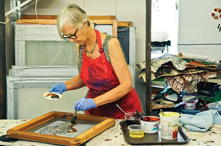 Textile artist Kerr Grabowski applying dye through a screen in a studio, demonstrating deconstructed surface design techniques
