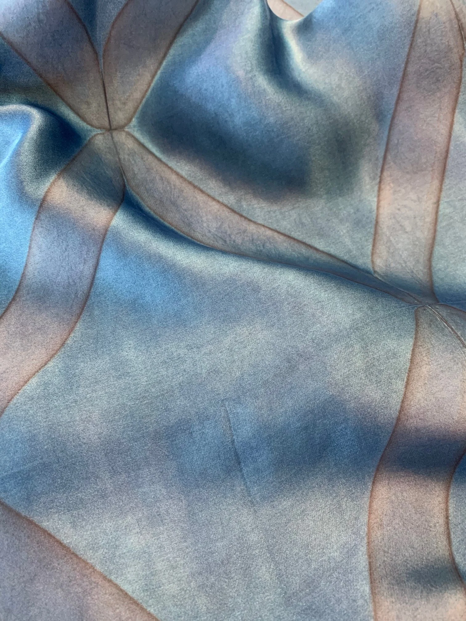 Close-up of a blue satin fabric with stitched seams and slight wrinkles.