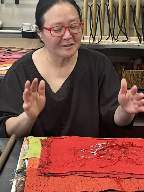 Paper artist Jiyoung Chung demonstrating Joomchi technique with layered hanji paper in a studio setting