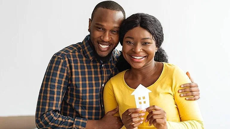 Un couple souriant tenant une clé en forme de maison