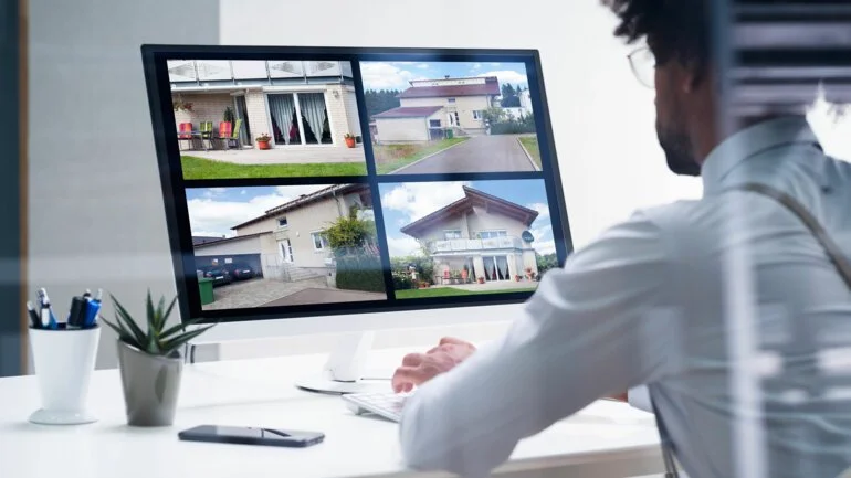 Un homme regarde des images de différentes maisons sur un écran d'ordinateur.