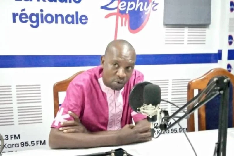 Homme assis à une table dans un studio de radio, parlant dans un microphone