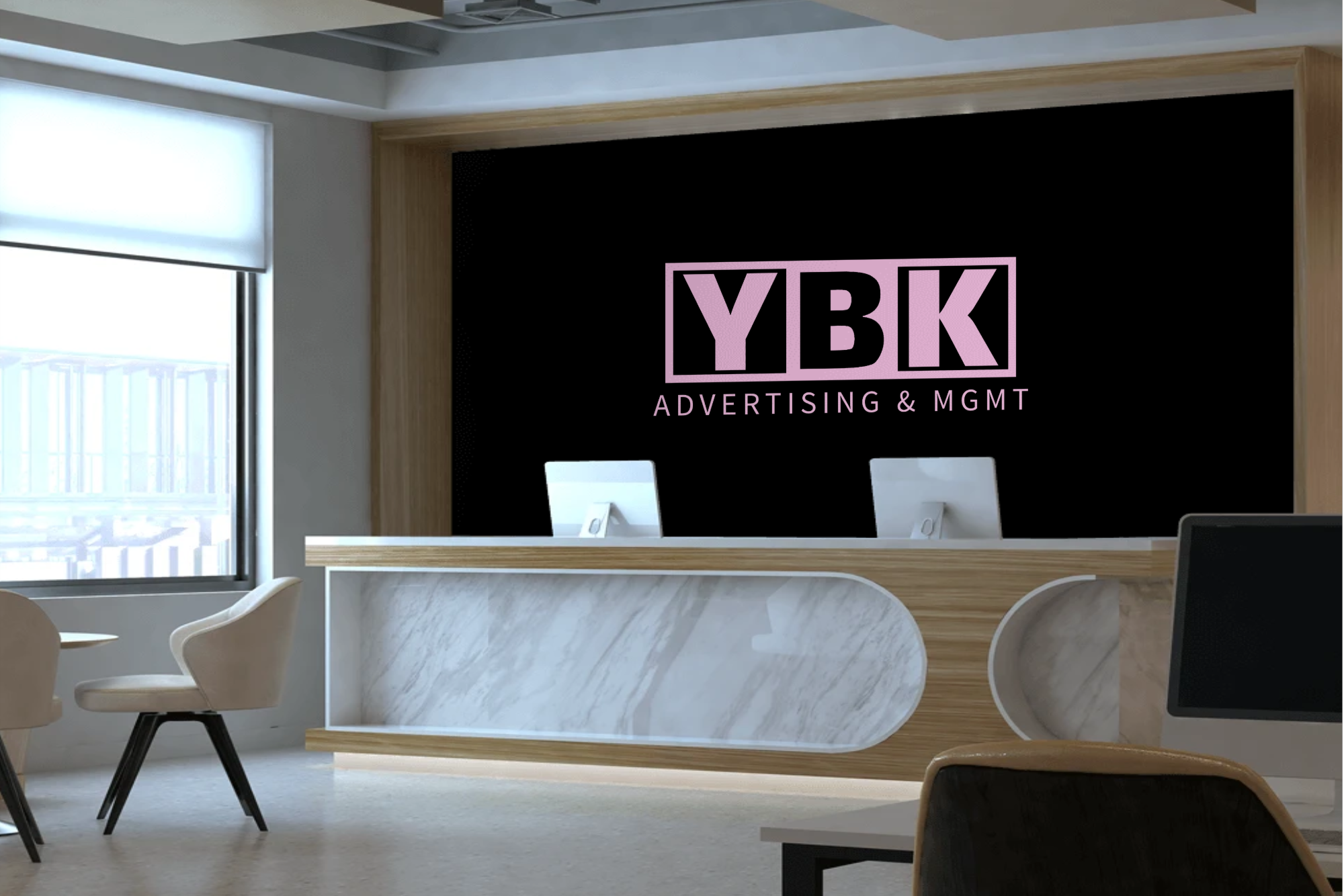 Reception area with a black wall displaying the YBK Advertising & MGMT logo in pink, a marble-front counter, and seating near a large window.