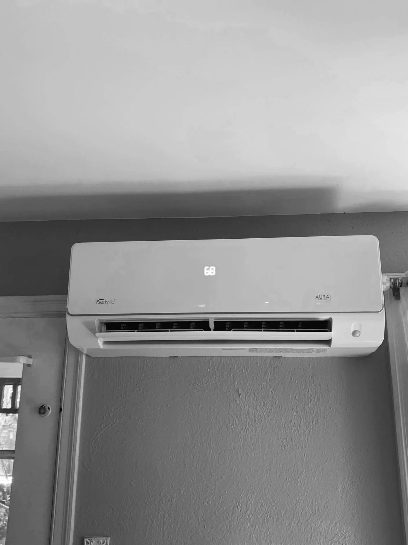 Wall-mounted air conditioning unit in a room, with digital display showing temperature.