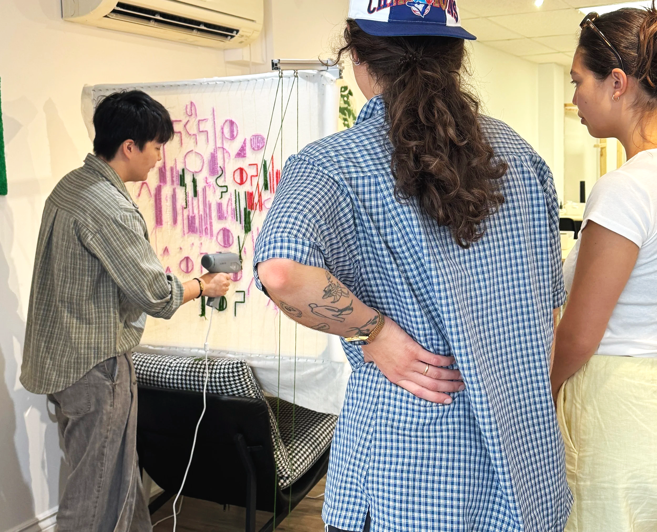 Instructors at Dotty Tuft Studio are showing the workshop guests a demo of how to use the tufting gun