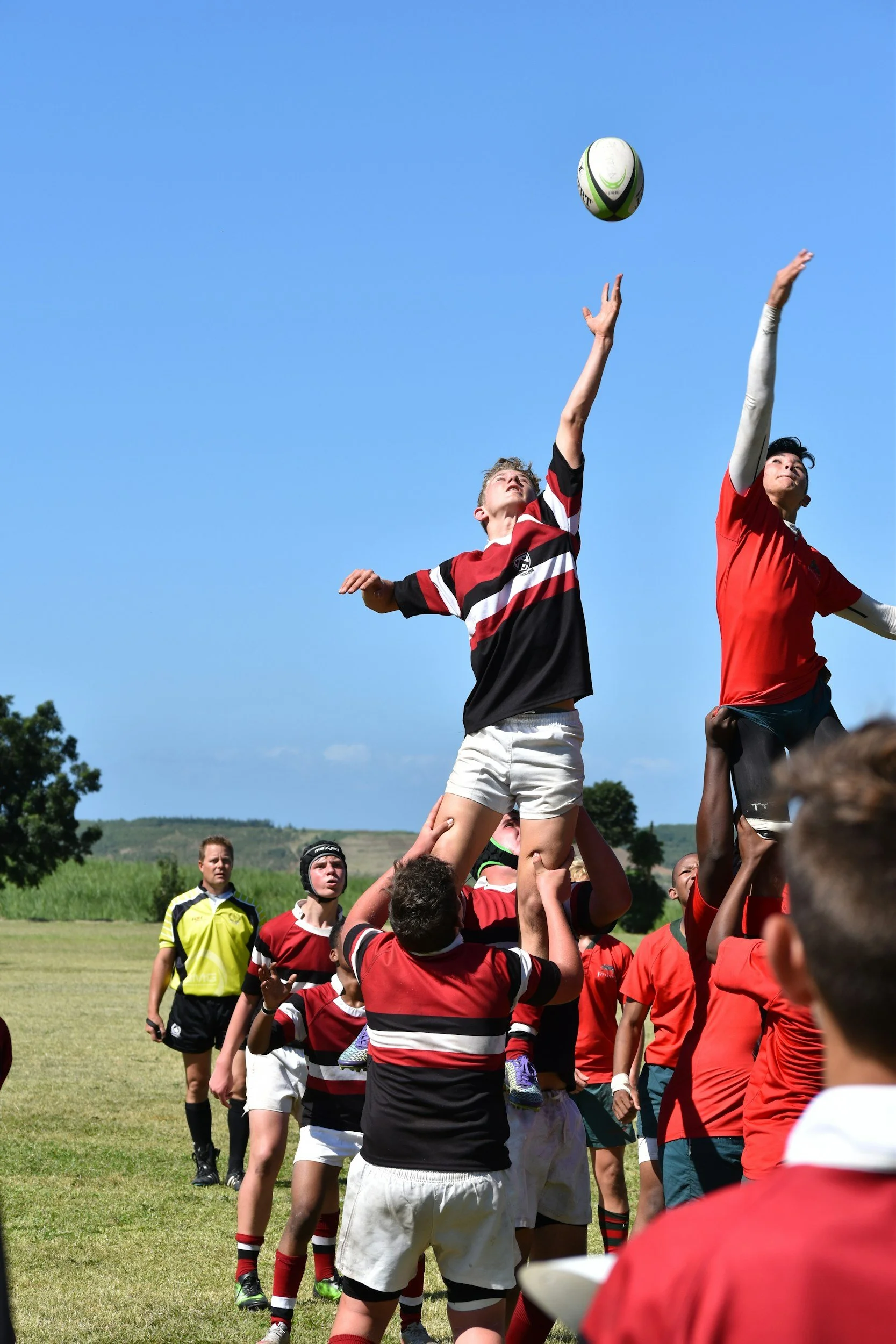Rugby players playing for a school team perform a line-out to catch the gilbert rugby ball during a match on a sunny day in dubai, uae.