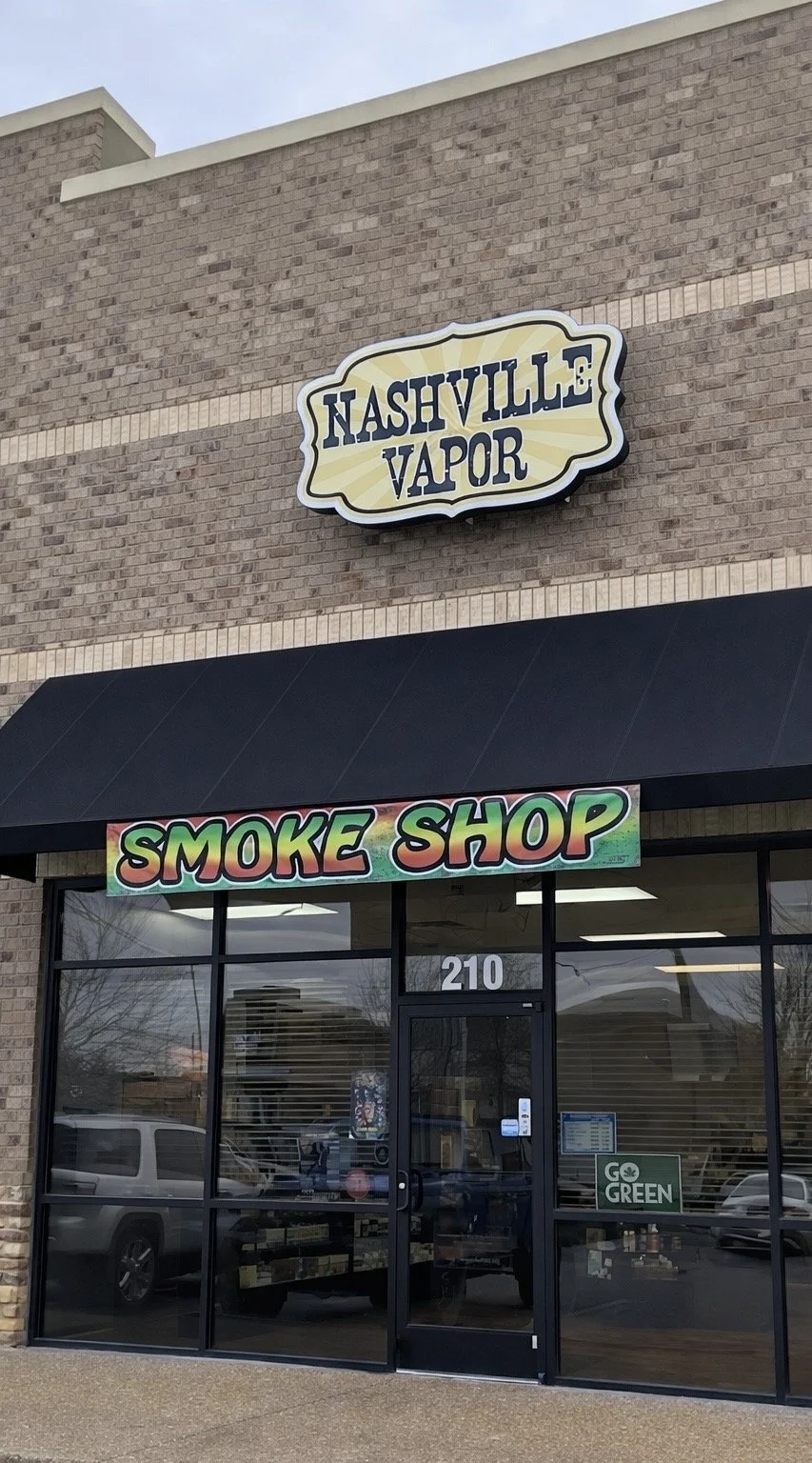 storefront with a sign that says 'Nashville Vapor' and a colorful sign that says 'Smoke Shop' in front of the entrance.