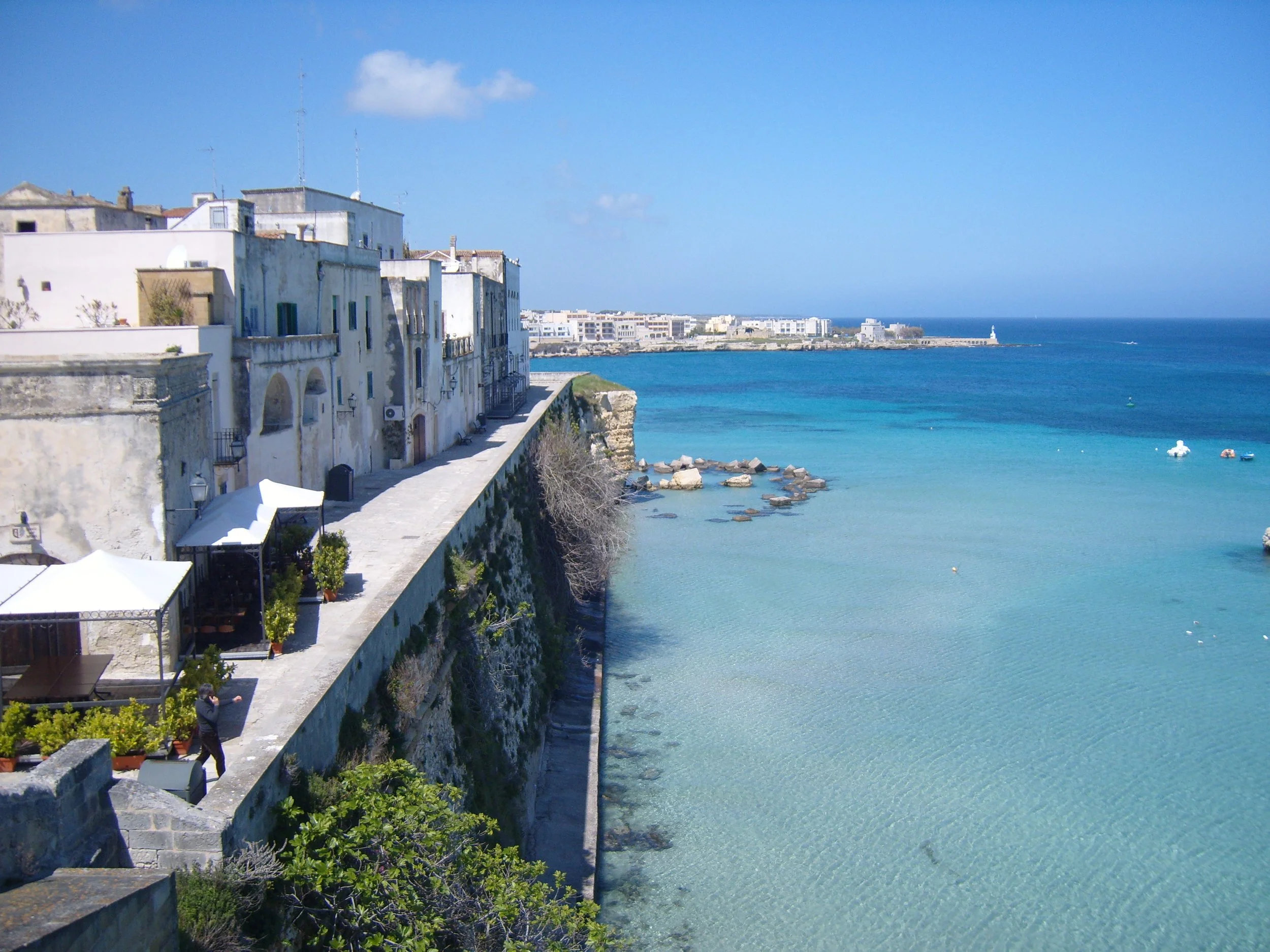 Blick auf Otranto im Salento mit hellen Häusern, Stadtmauer und klarem, türkisfarbenem Meer als Zielpunkt der Camperroute entlang der Adria.