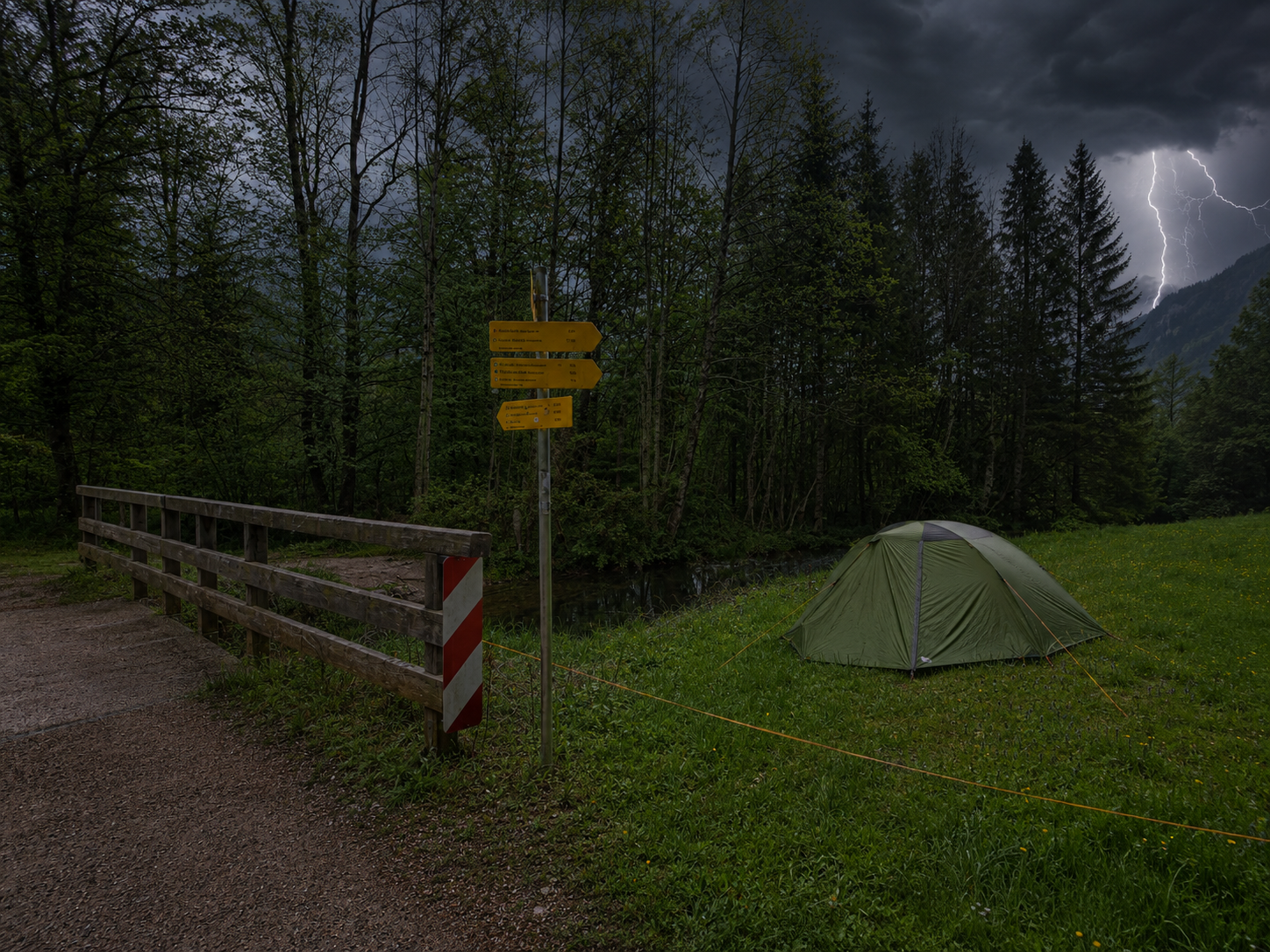 Zelt auf einer Wiese bei aufziehendem Sturm und Gewitter, daneben ein Wegweiser und eine Brücke am Waldrand.