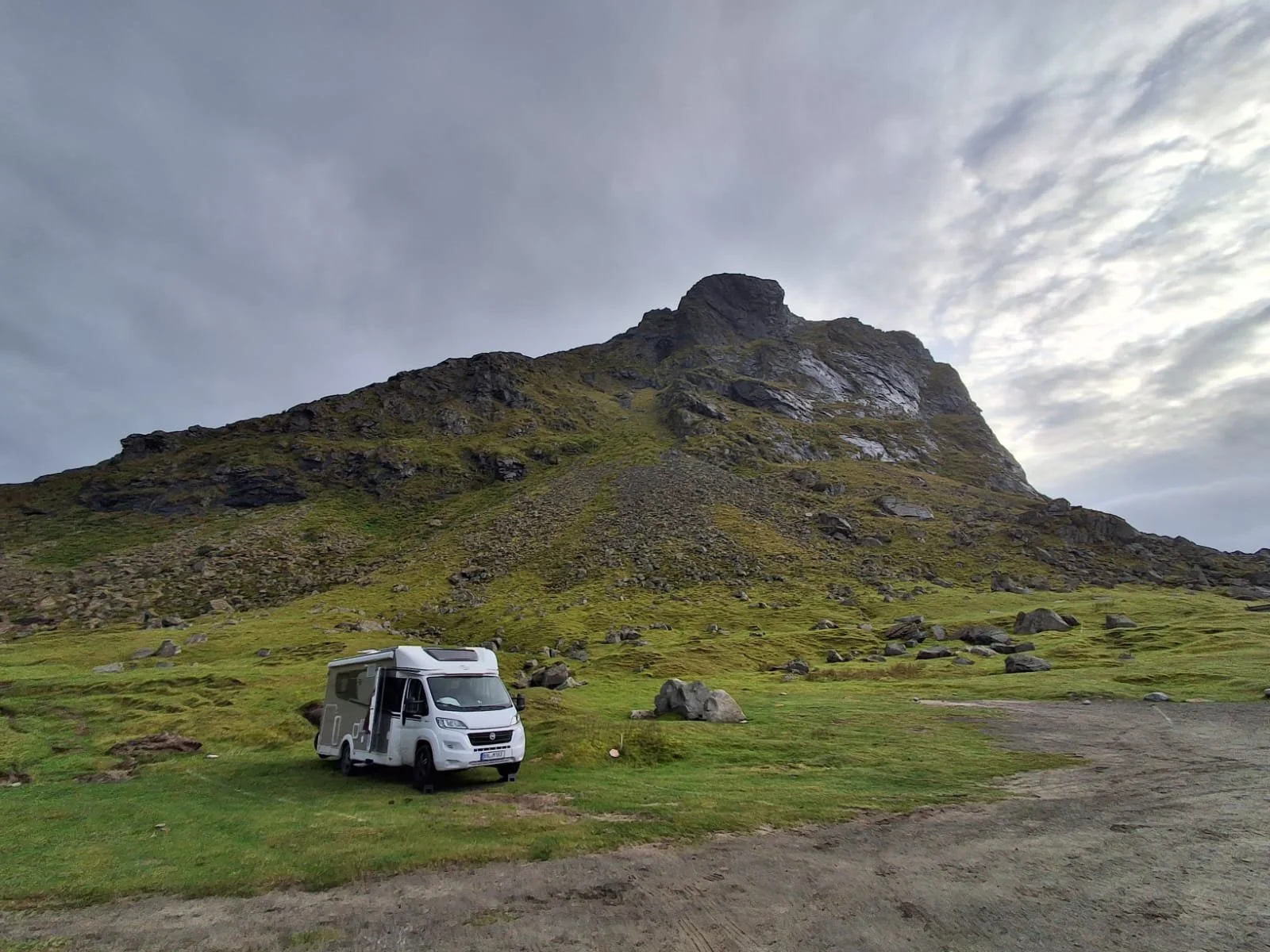 Wohnmobil in weiter grüner Berglandschaft in Norwegen vor einem großen felsigen Berg.