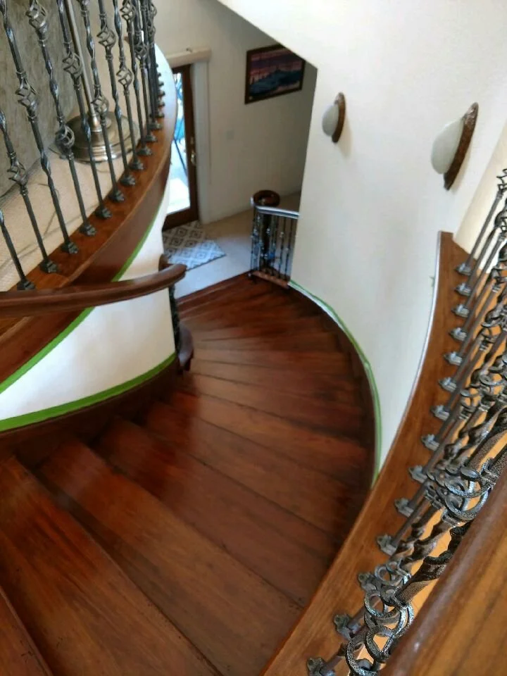 Curved wooden staircase featuring smooth wood treads and decorative iron balusters in a residential home.