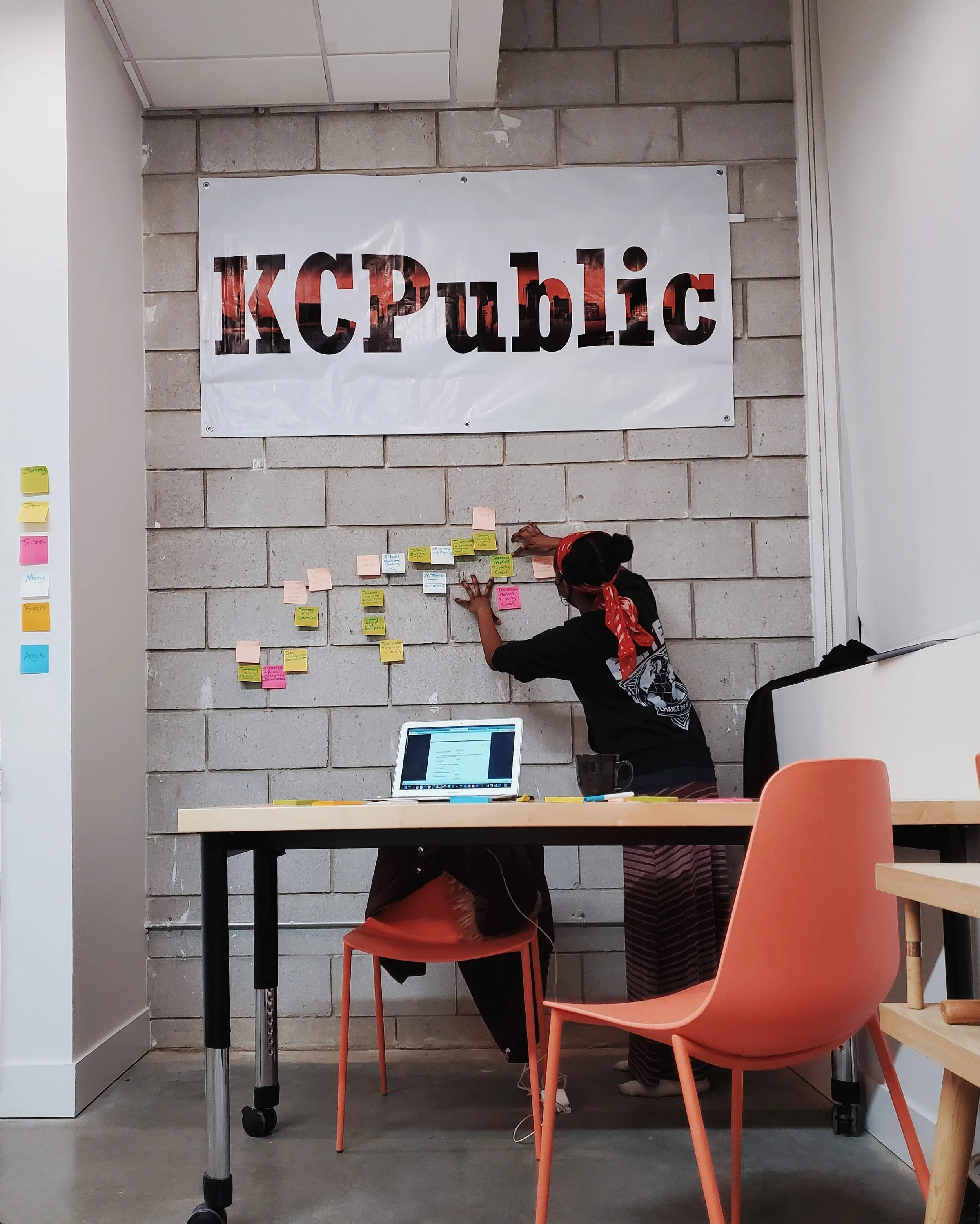 KC Public Theatre's resident playwright, Prisca Jebet-Kendagor, arranging sticky notes on the KC Public office wall, outlining her new play.