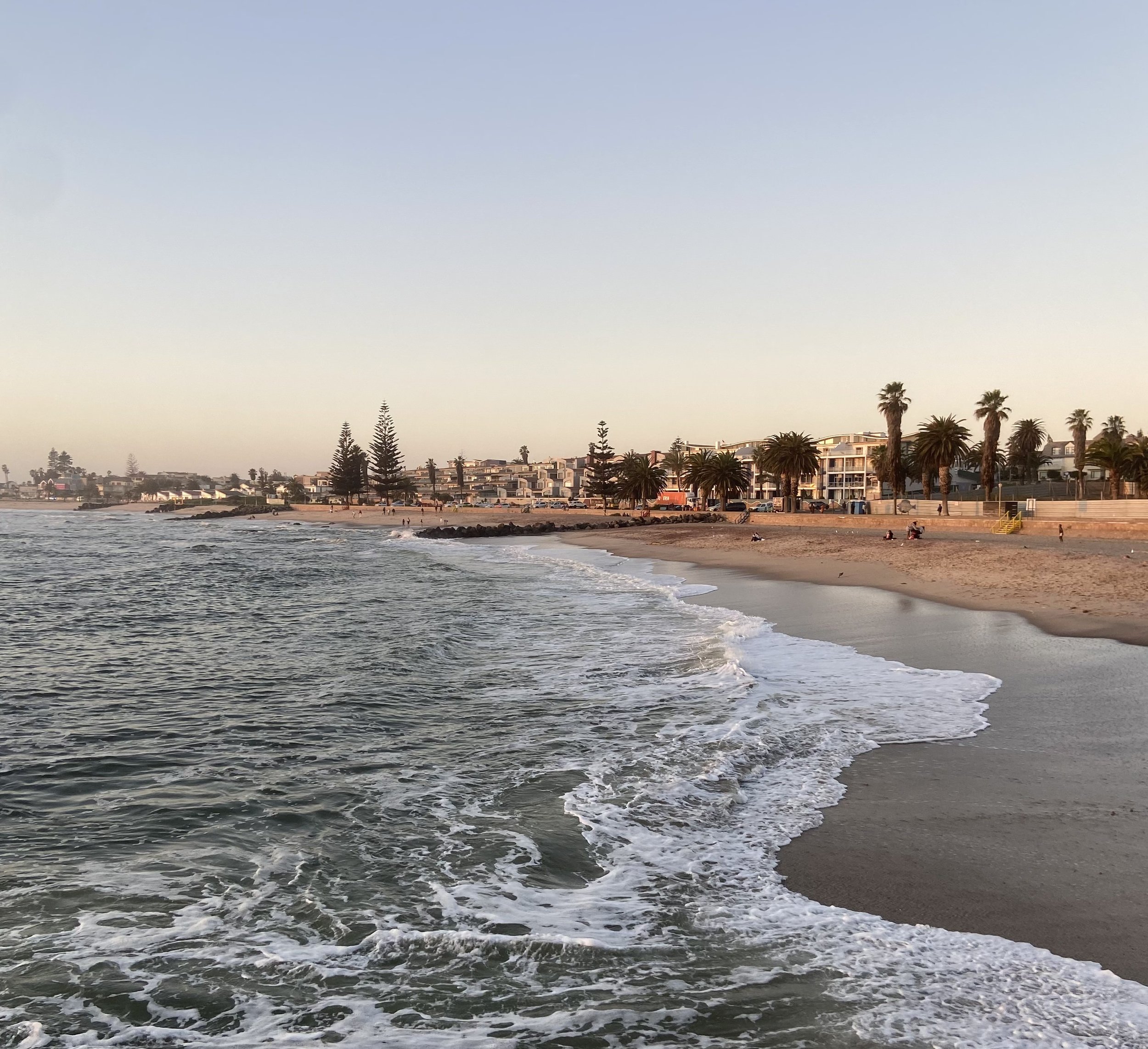 Ocean waves crashing on the sandy beach promenade in coastal Swakopmund Namibia at sunset.