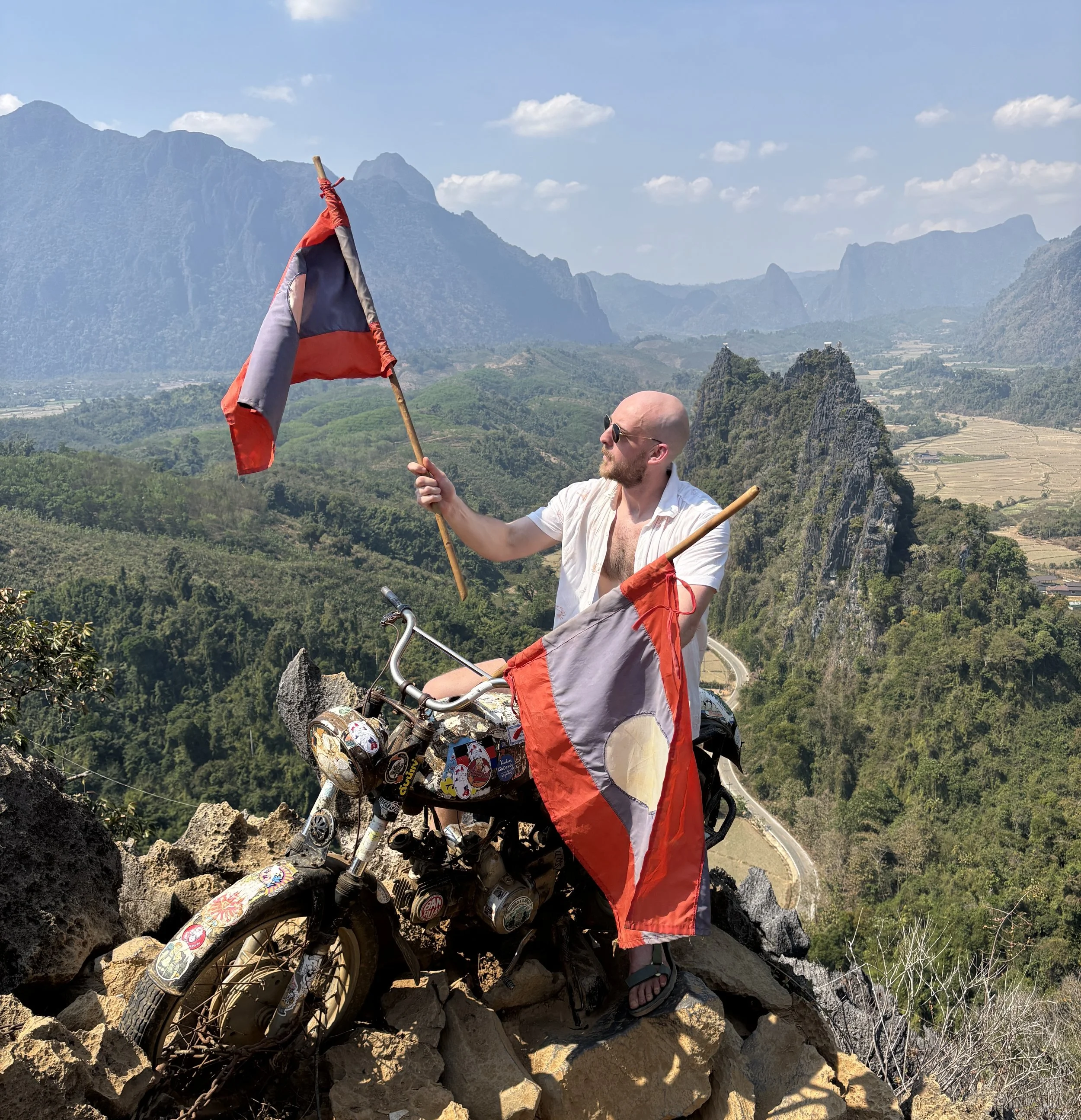 A man sat on a motorbike in the countryside of Laos near Vang Vieng.