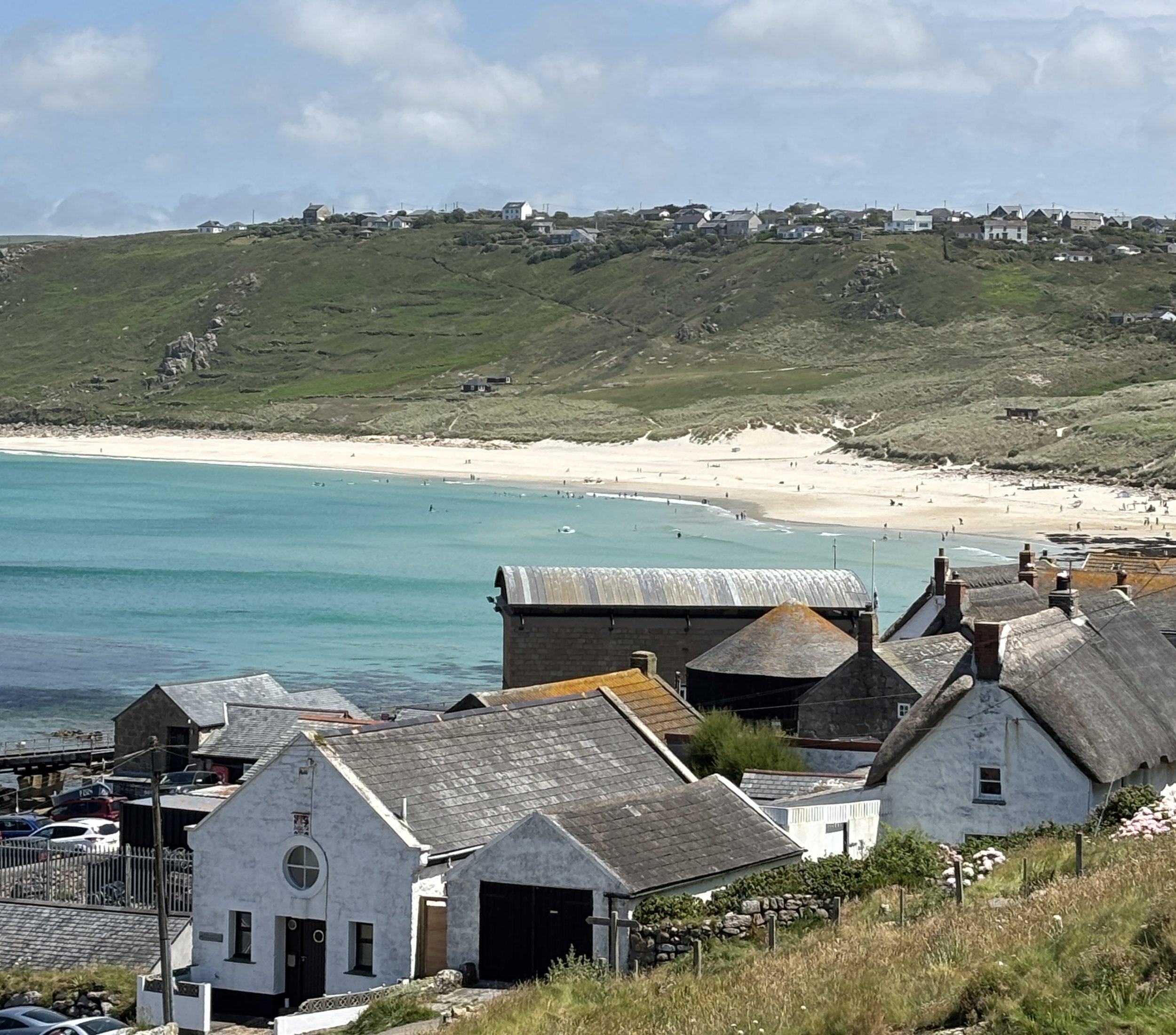 Sennen Beach with thatched roof cottages and sprawling beach.