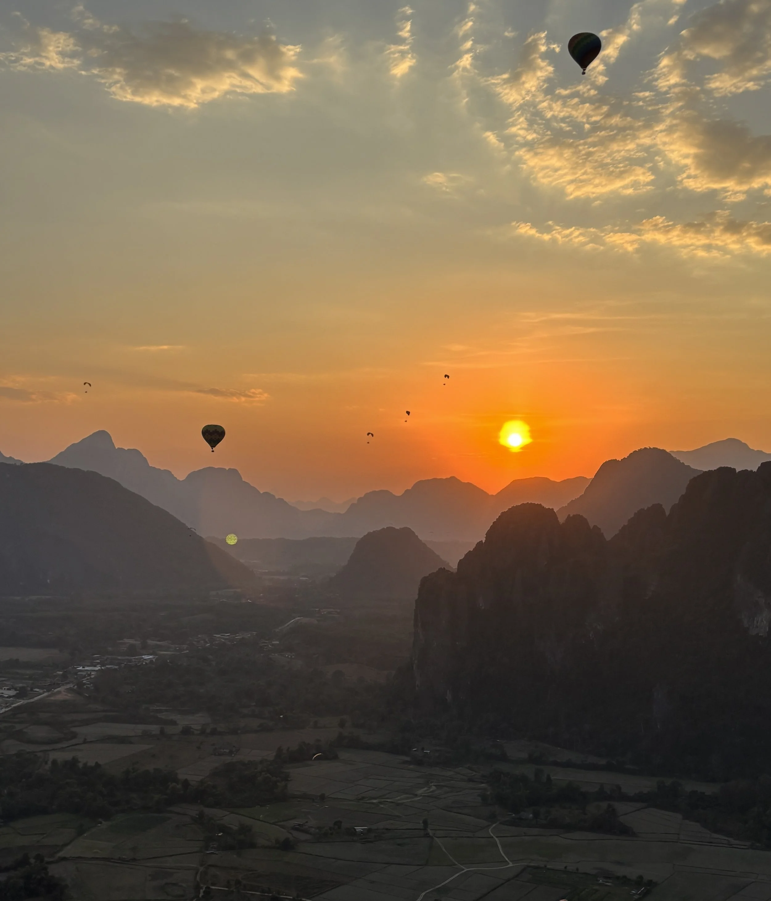 Sunlight breaking through morning mist over the winding Mekong River and lush green mountains of northern Laos.