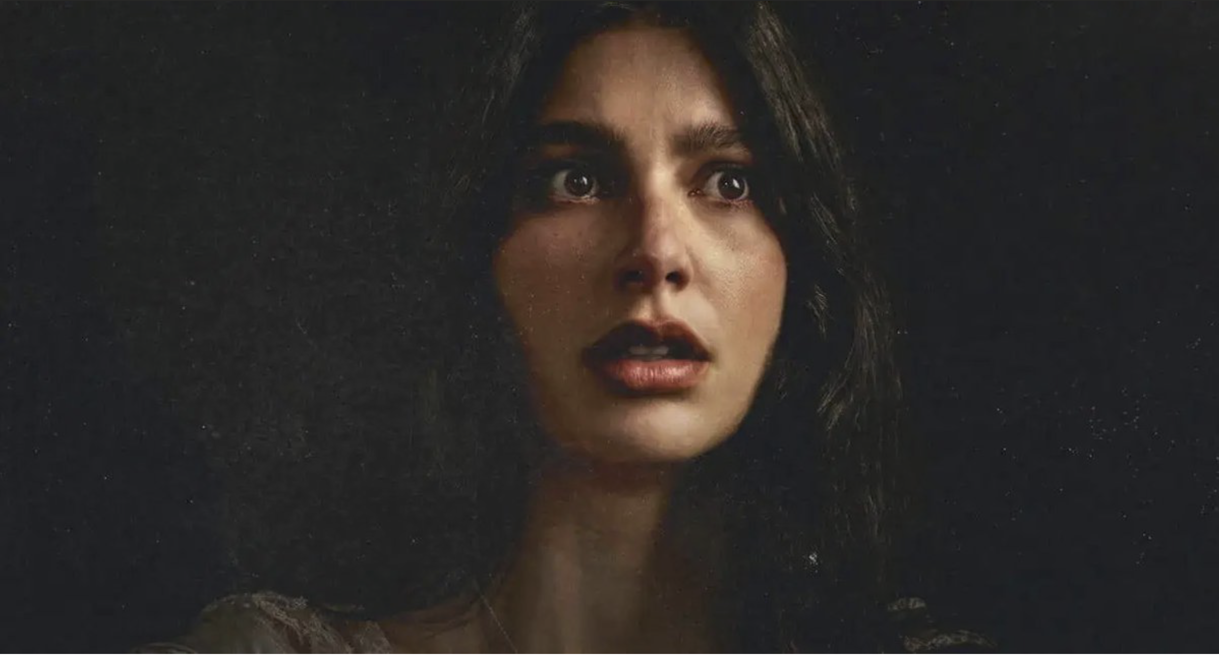 Close-up of a woman's face with an expression of surprise or shock, set against a dark background.