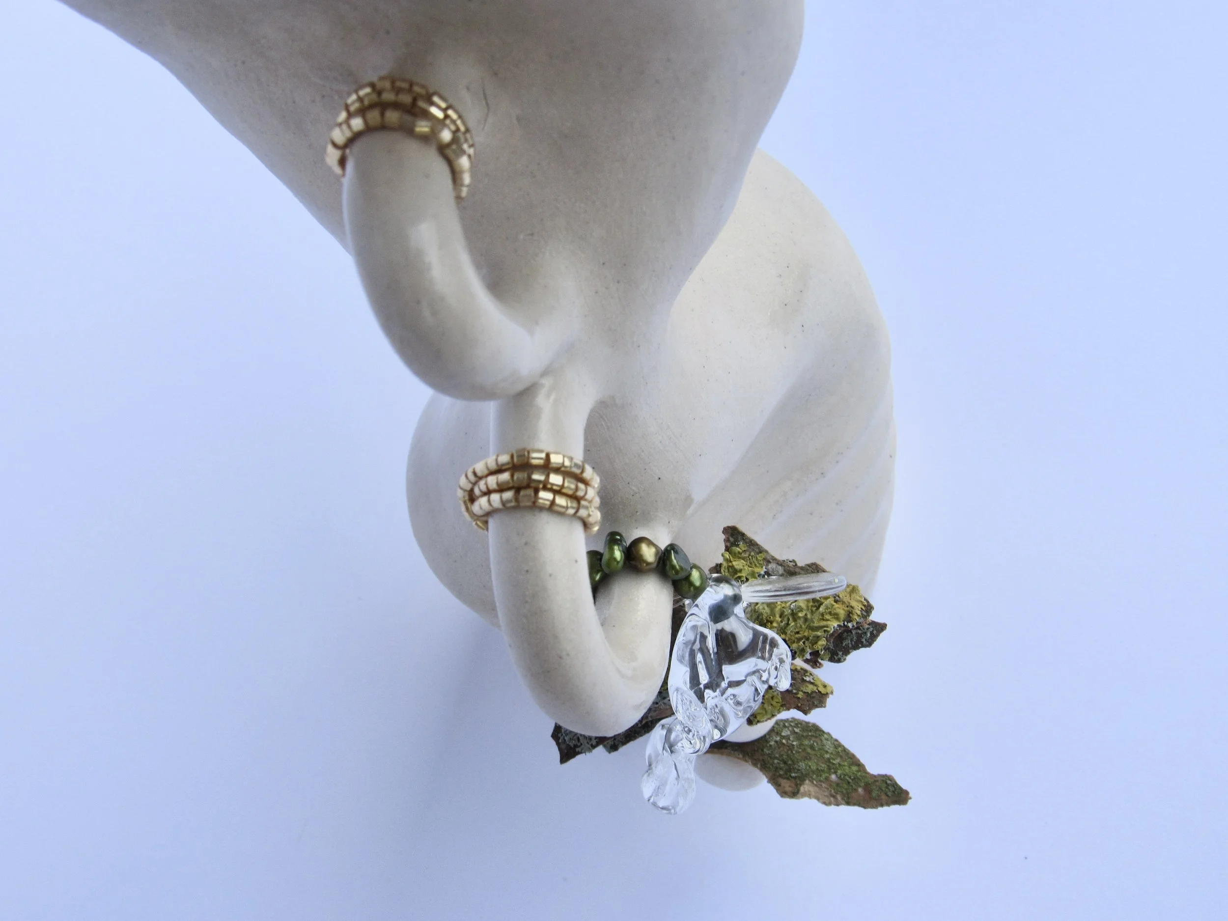 A close-up of a white statue with jewelry and decorative elements, seen against a blue sky.