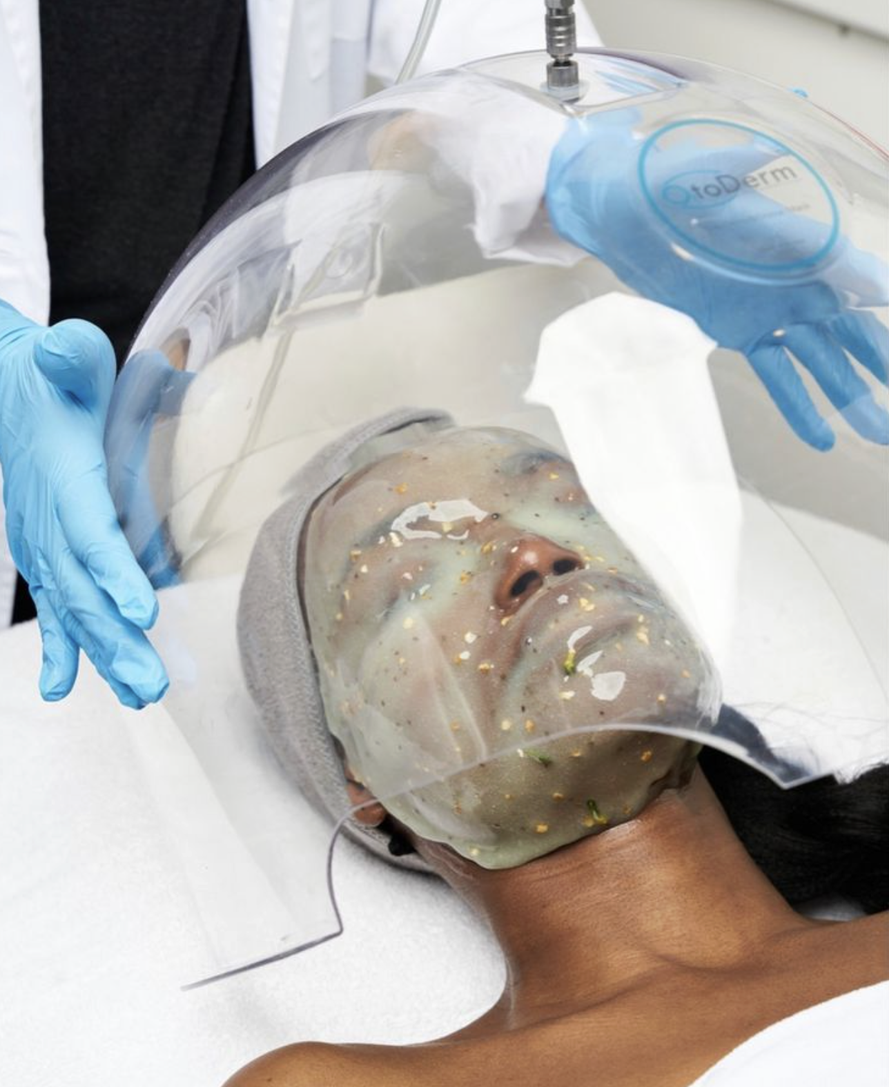 Medical professional handling a patient in a hyperbaric oxygen chamber, where the patient is lying down with a transparent mask over their face, connected to the chamber for treatment.