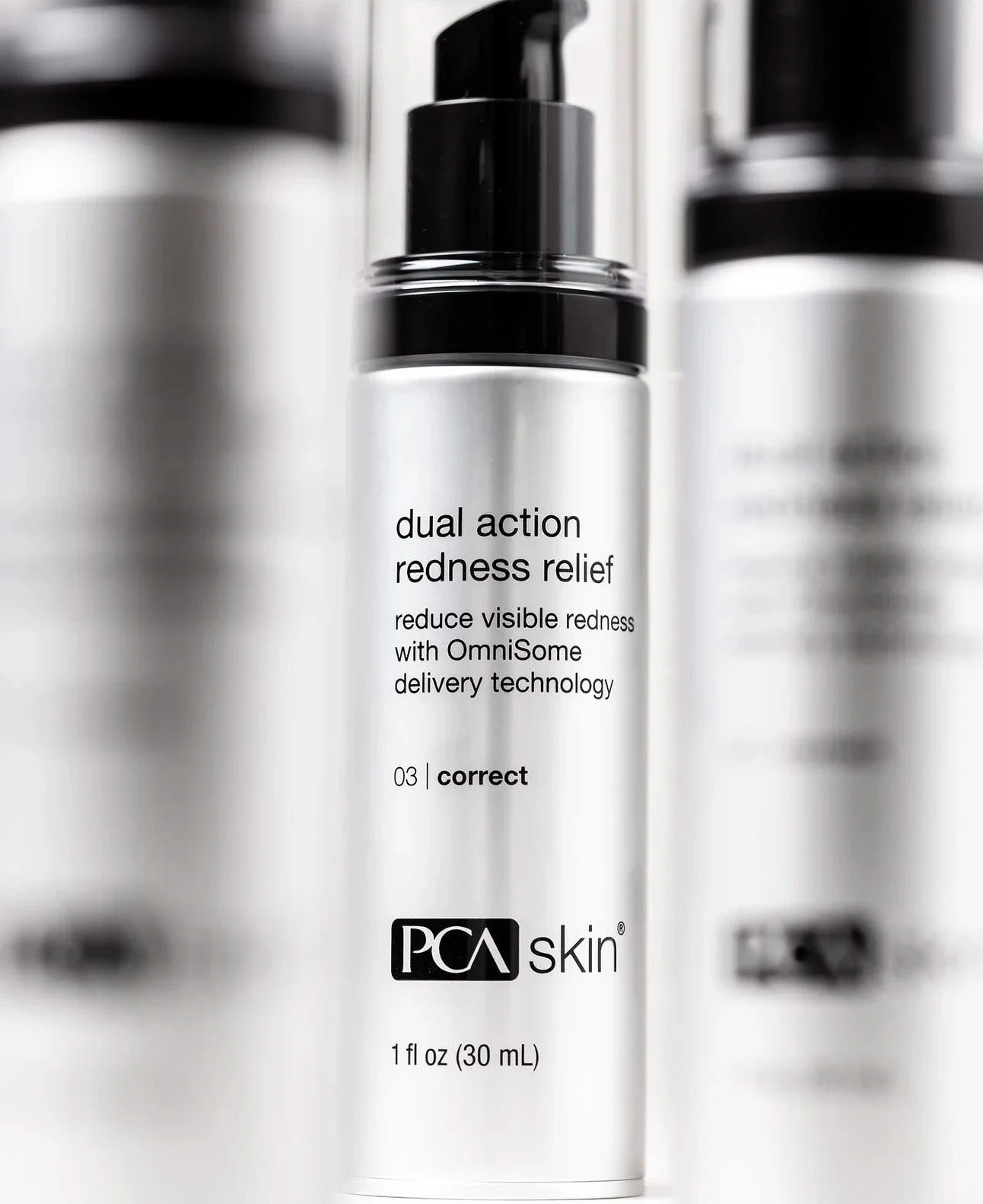 A skincare product in a white bottle with a black cap, labeled "dual action redness relief" by PCA Skin, indicating it reduces visible redness with OmniSome delivery technology.