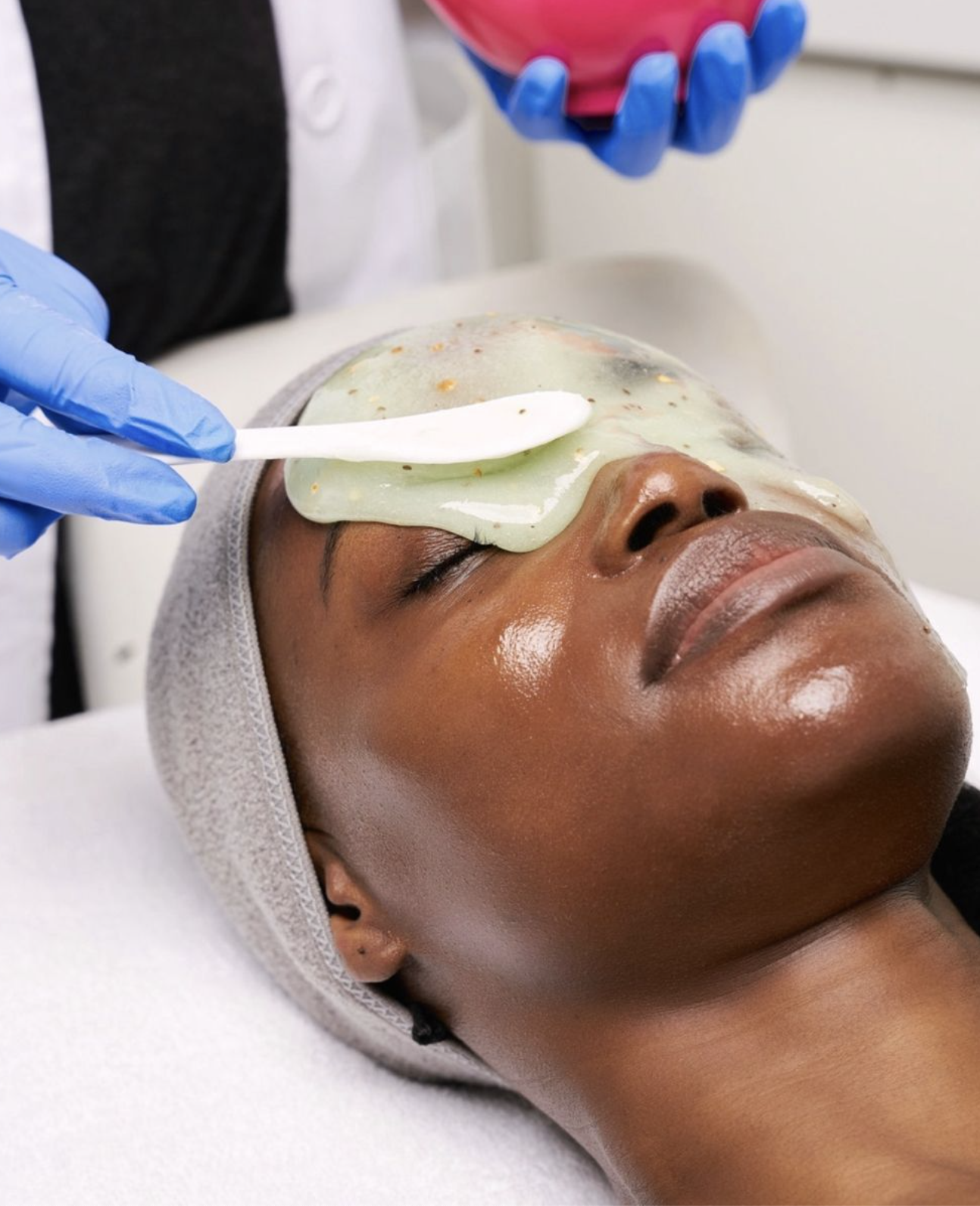 A woman relaxing with a facial mask applied to her face in a spa or skincare clinic.