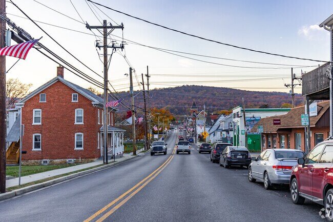 Picture of downtown Thurmont, Maryland with shops, houses, and cars. A soft hill is in the background.