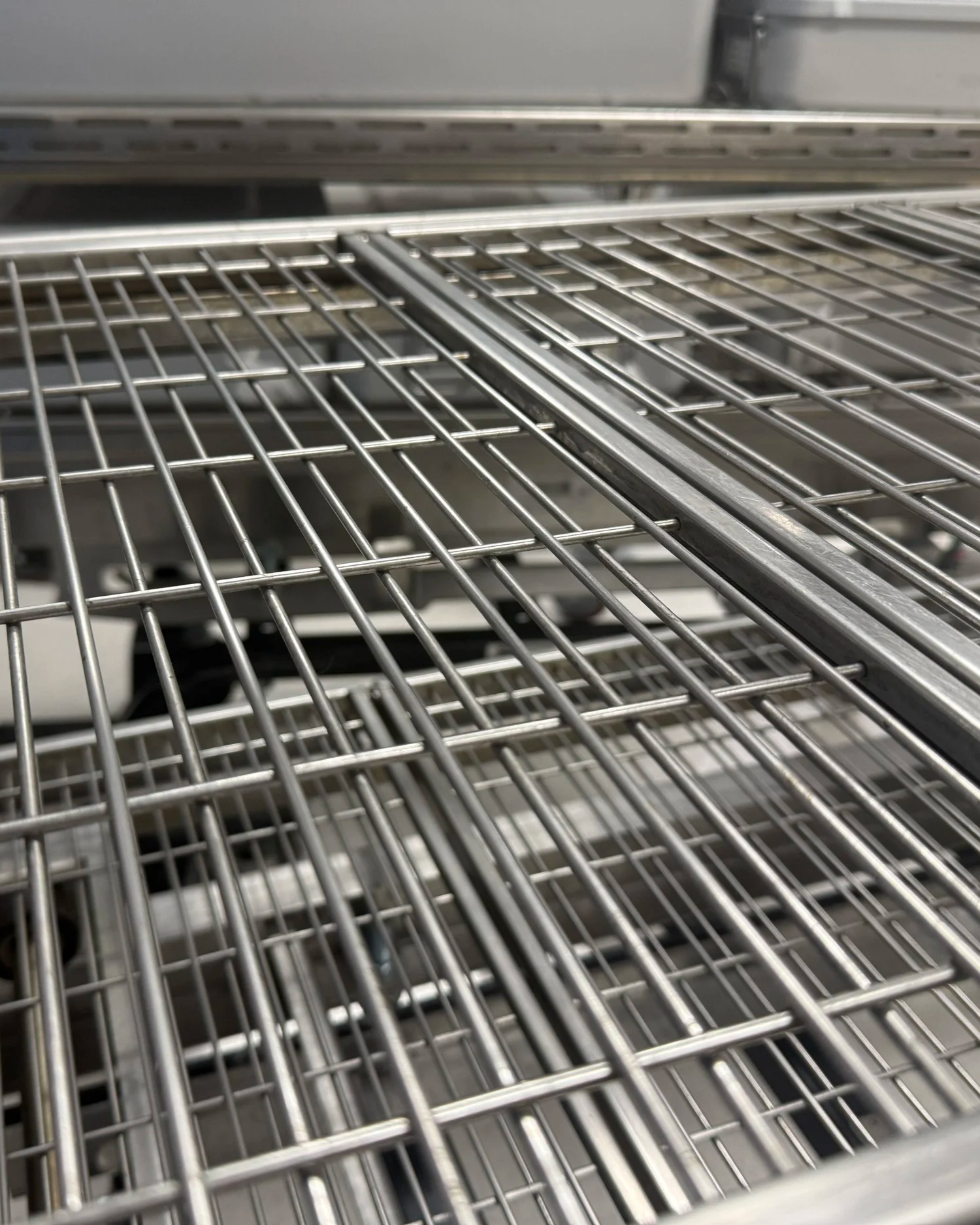 Close-up of empty metal wire shelving racks that have had bioburden removed in a sterile processing department setting.