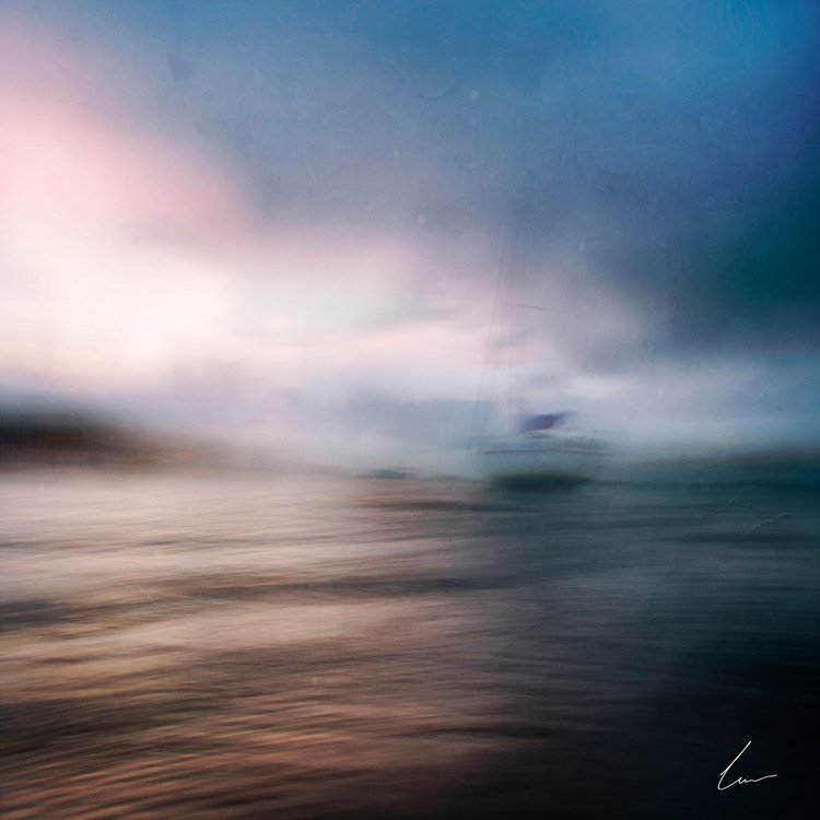 Blurred image of the ocean with a cloudy sky and a ship or boat in the distance.