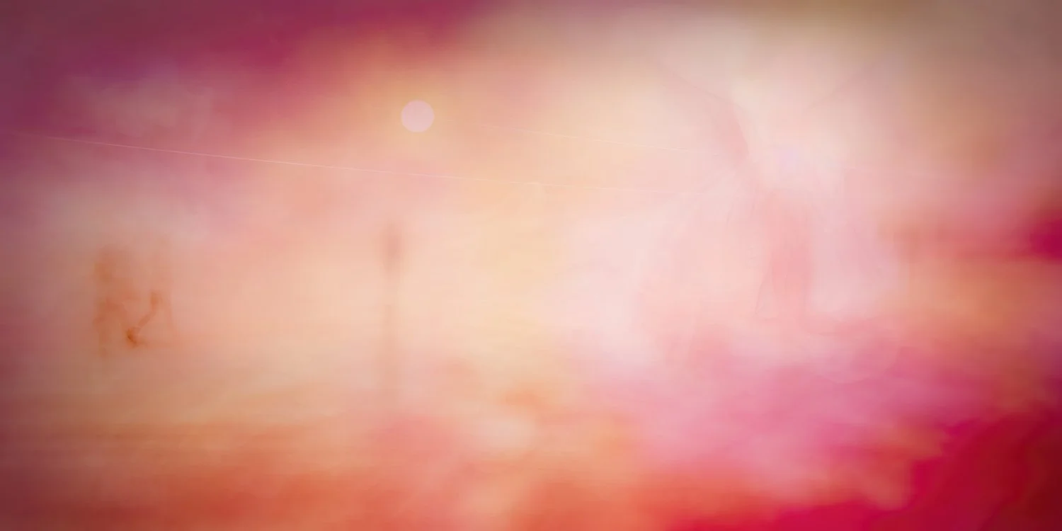 Abstract pink, peach, and purple blurred background with soft gradients and light spots.