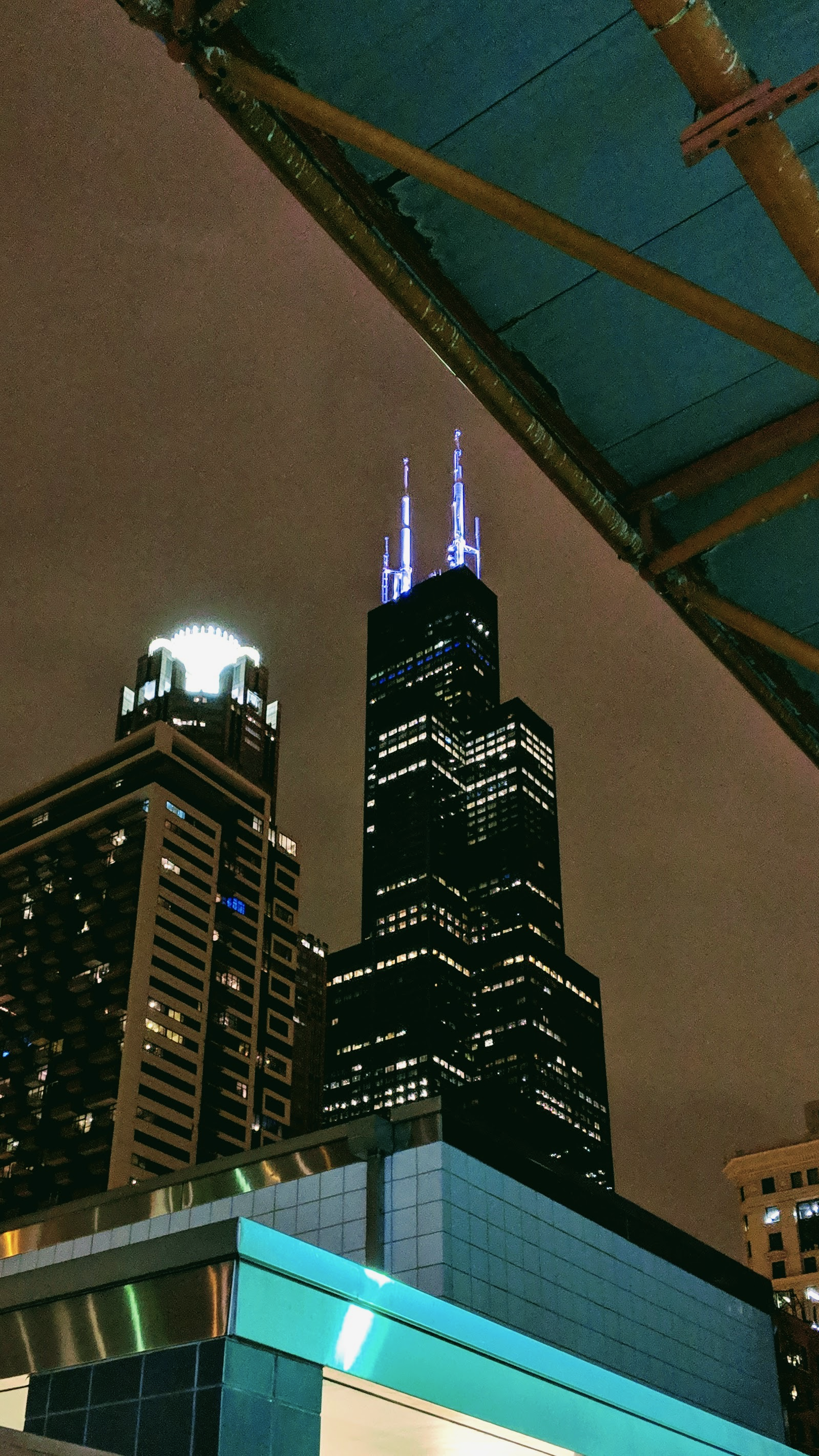 Nighttime view of downtown Chicago with the Willis Tower illuminated and other skyscrapers visible.