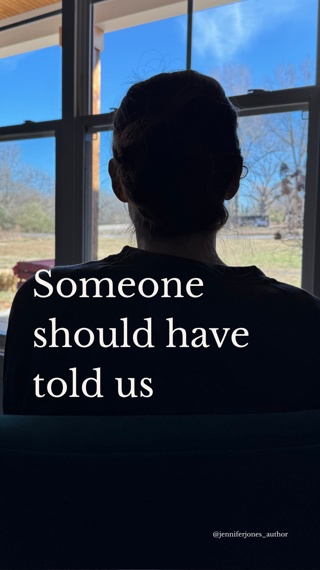 A person with dark hair sitting indoors facing a window, with a view of trees and a clear blue sky outside. The person is darkly silhouetted against the outside light, and there is text overlaid on the image that reads 'Someone should have told us' and a small credit '@jenniferjones_author'.