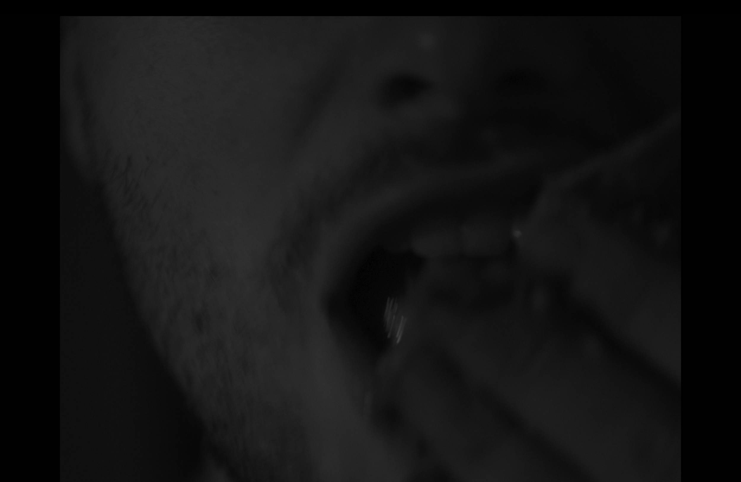 A close-up black-and-white photo of a person's face, partially visible, with lips slightly parted and a hand near the mouth. Still from the short film, FISH (2025).