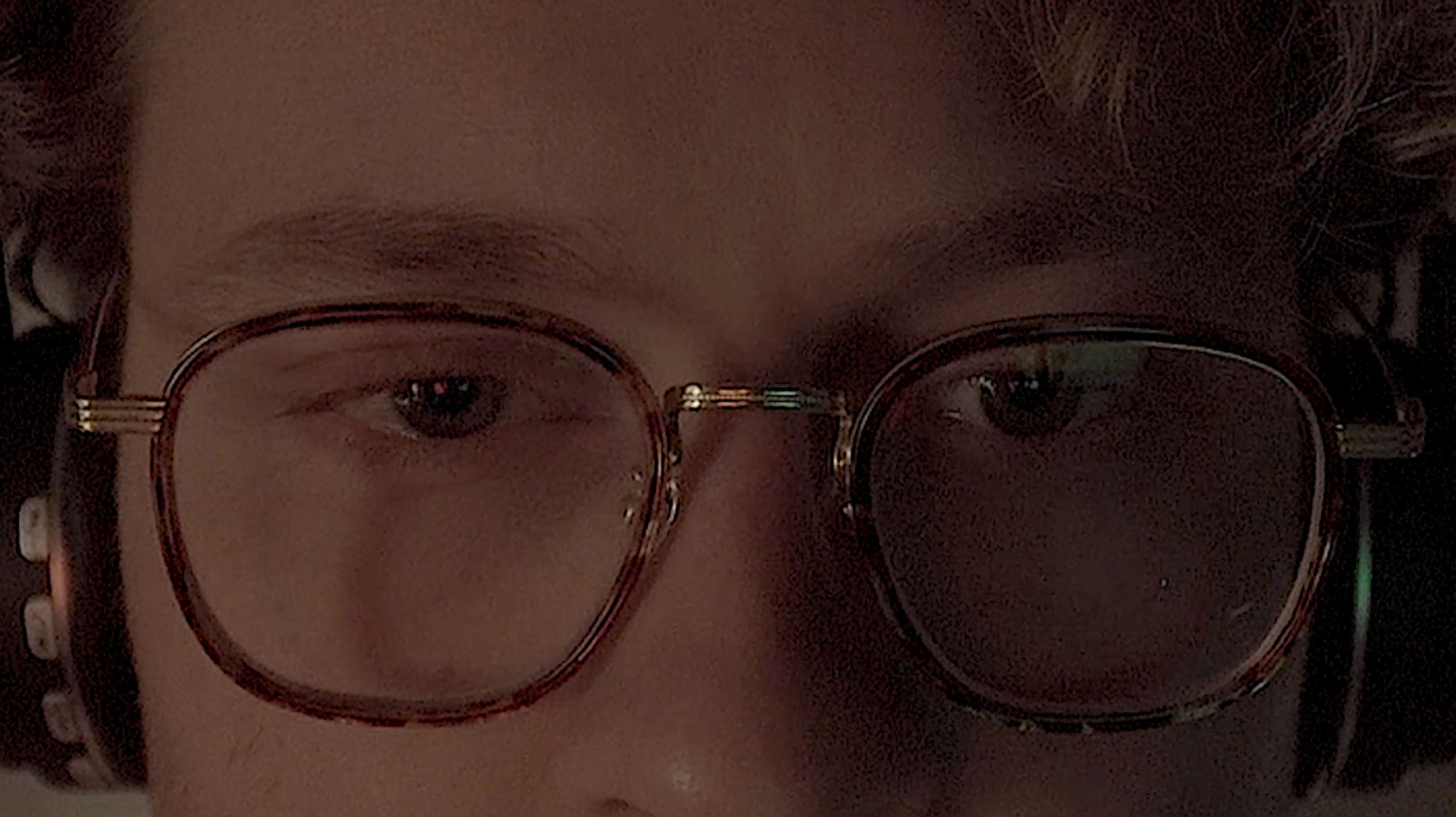 Close-up of a person's face wearing glasses, with a focus on their eyes and eyebrows. Still of Jacob Leo Marino from NAME (2026).
