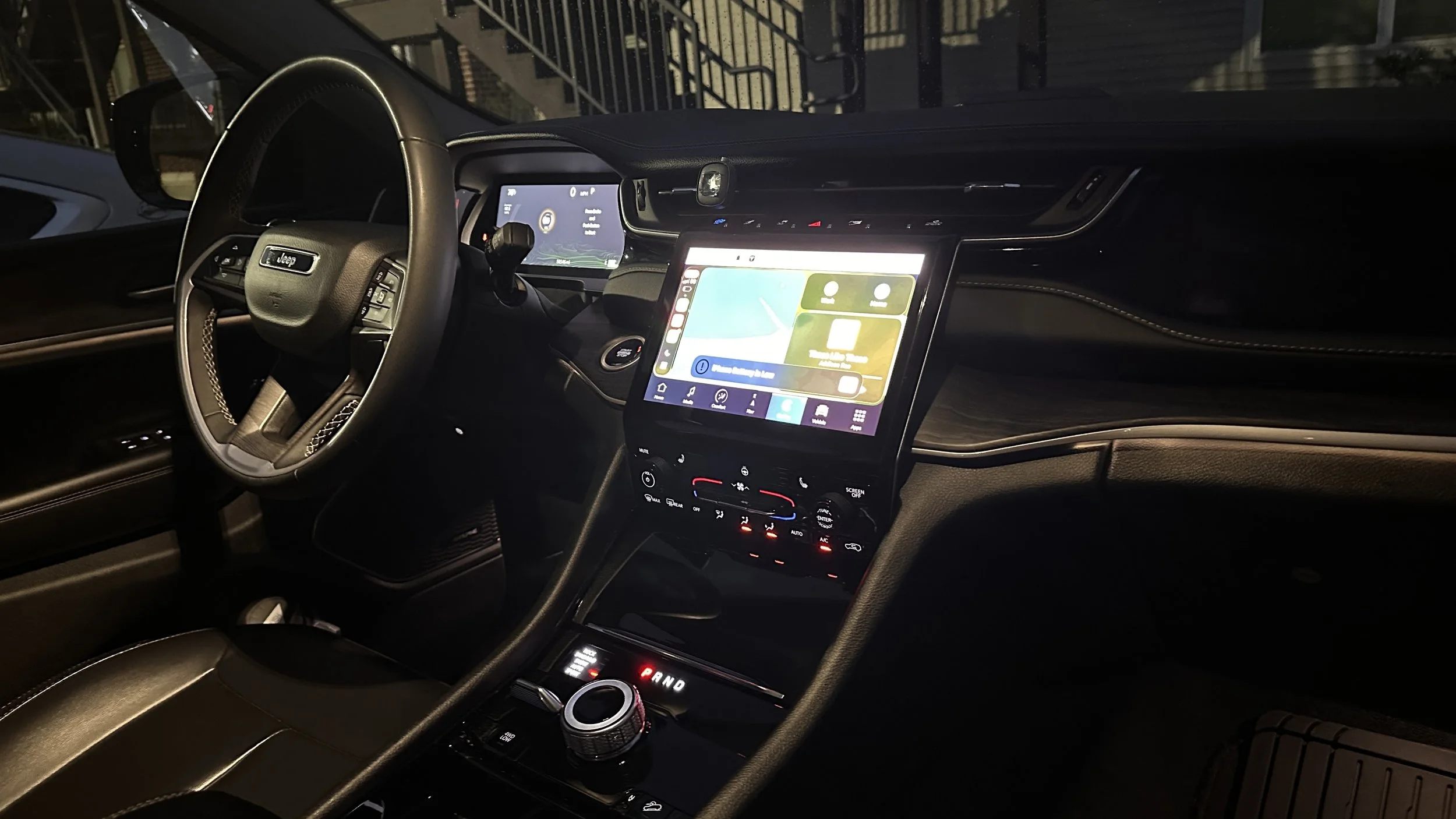 Interior of a modern car showing a steering wheel, digital dashboard, and central touchscreen display at night.