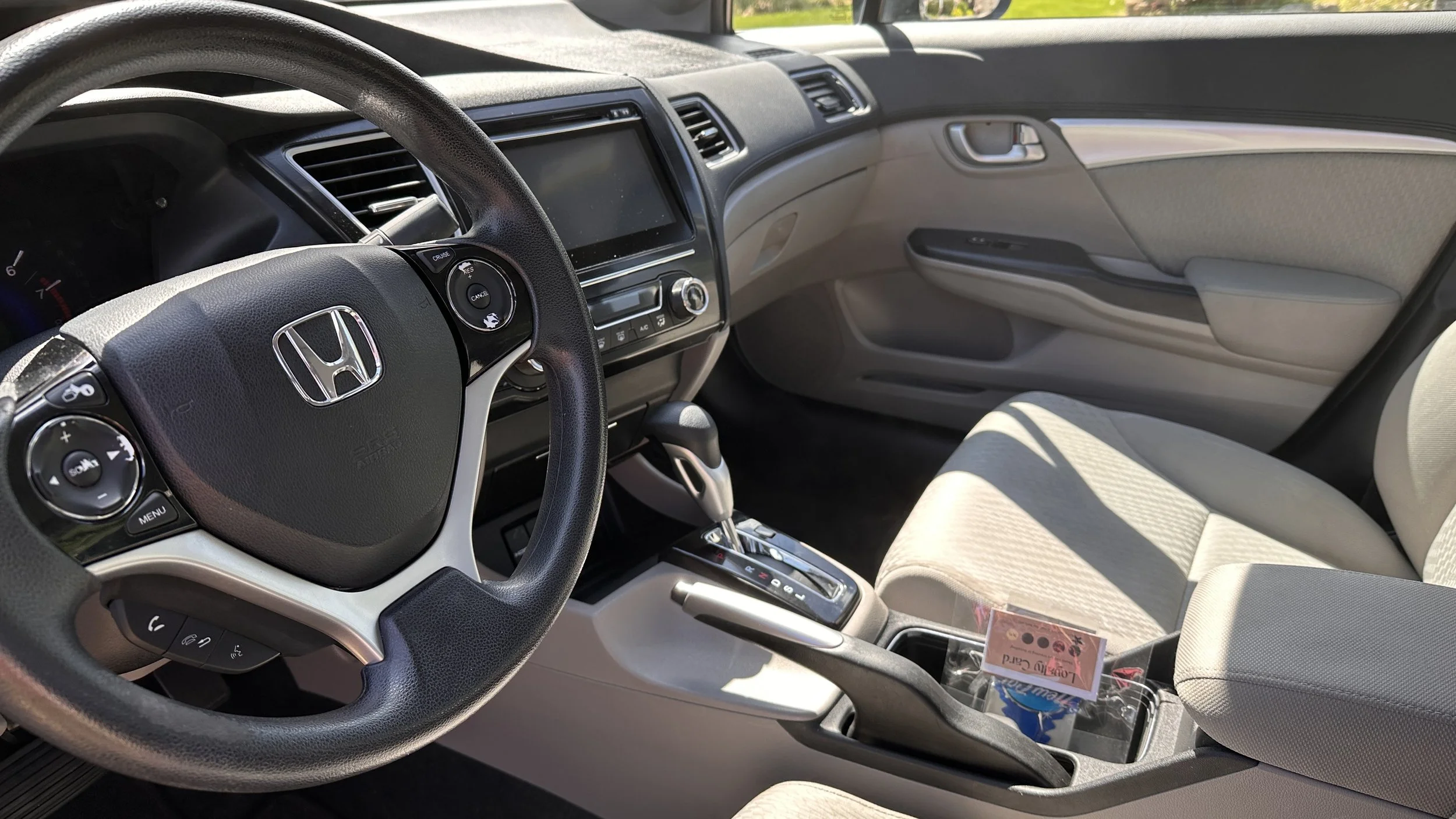 Interior of a Honda vehicle showing the steering wheel, dashboard, front passenger seat, and center console with gear shift.
