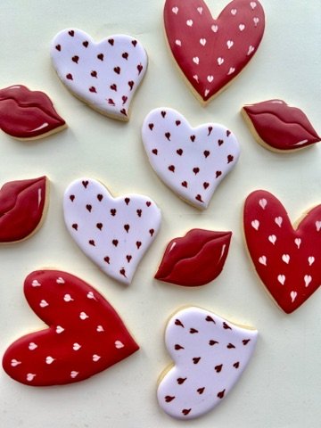 Valentine's Day cookies decorated as hearts and lips, with red and white icing featuring small hearts and lips.