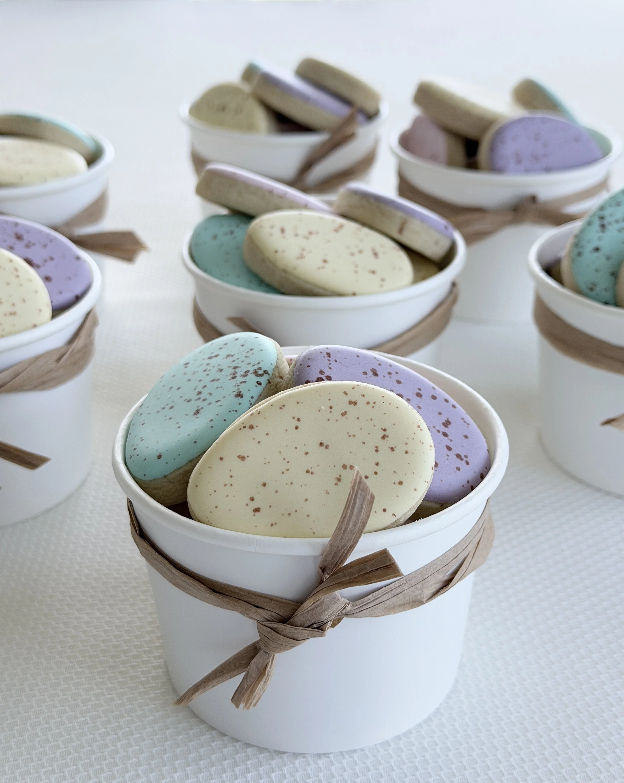 White gift box filled with pastel-colored speckled macarons.