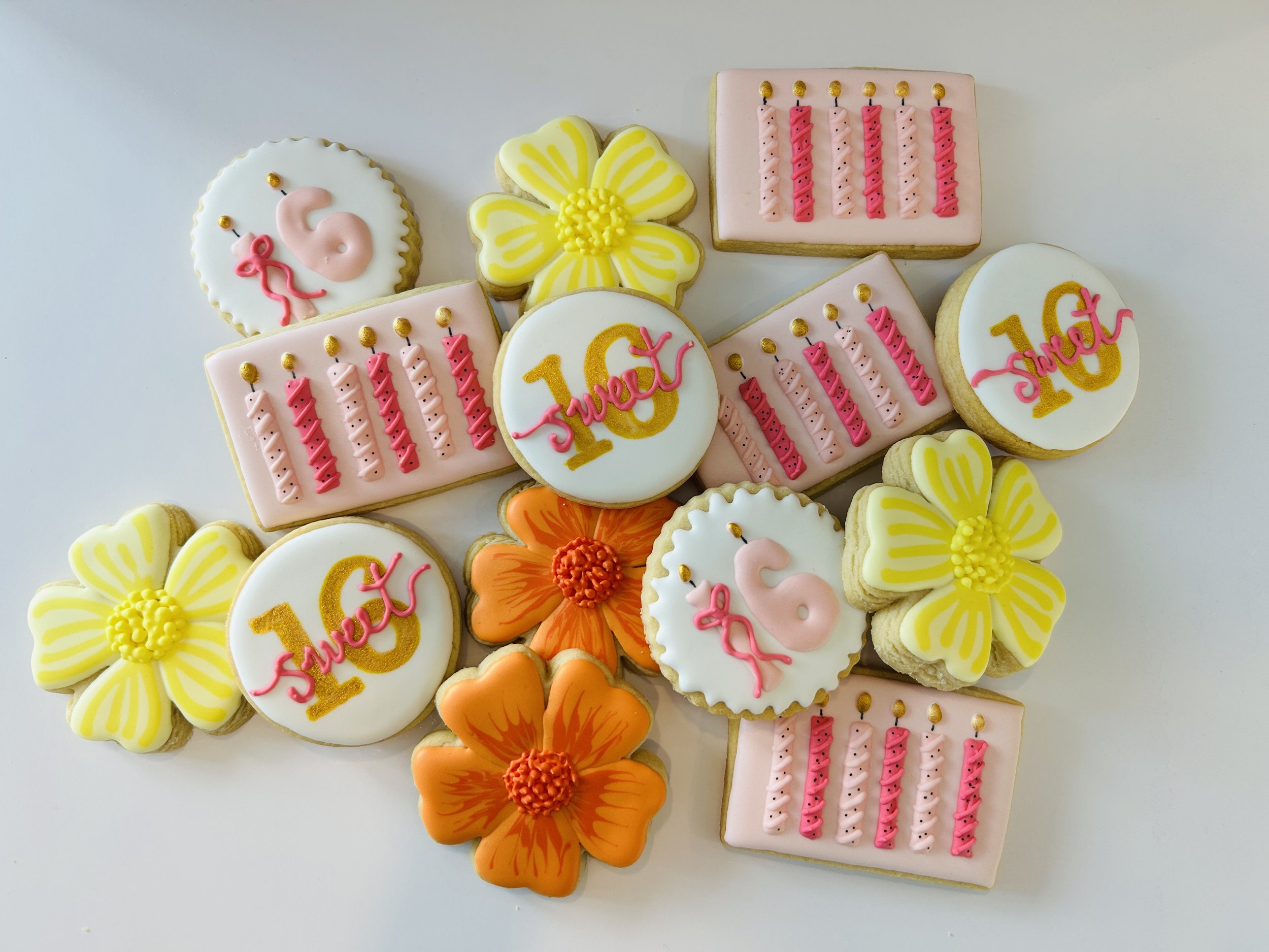 Decorated birthday cookies with pink and yellow themes, including candles, the number 10, a swan, and flowers.