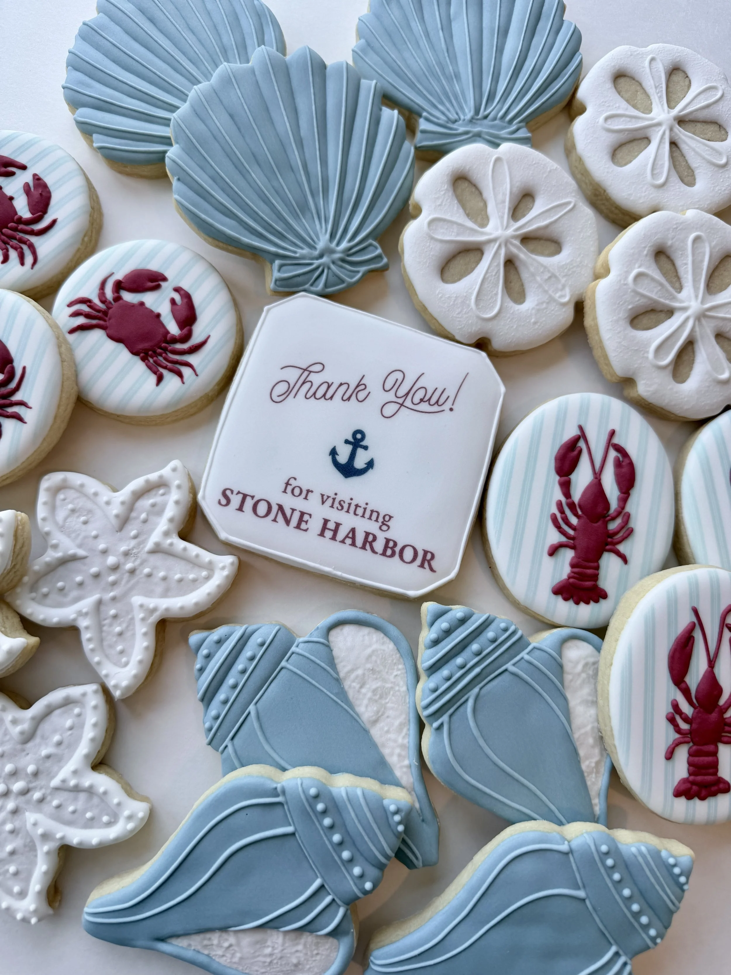 Decorated cookies with summer and nautical themes including blue seashells, white sand dollars, and red lobsters, along with a thank you note for visiting Stone Harbor.