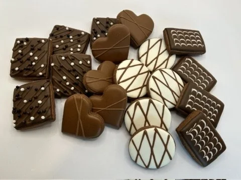 Assorted chocolates, including square and heart-shaped pieces with decorative icing patterns and sprinkles.