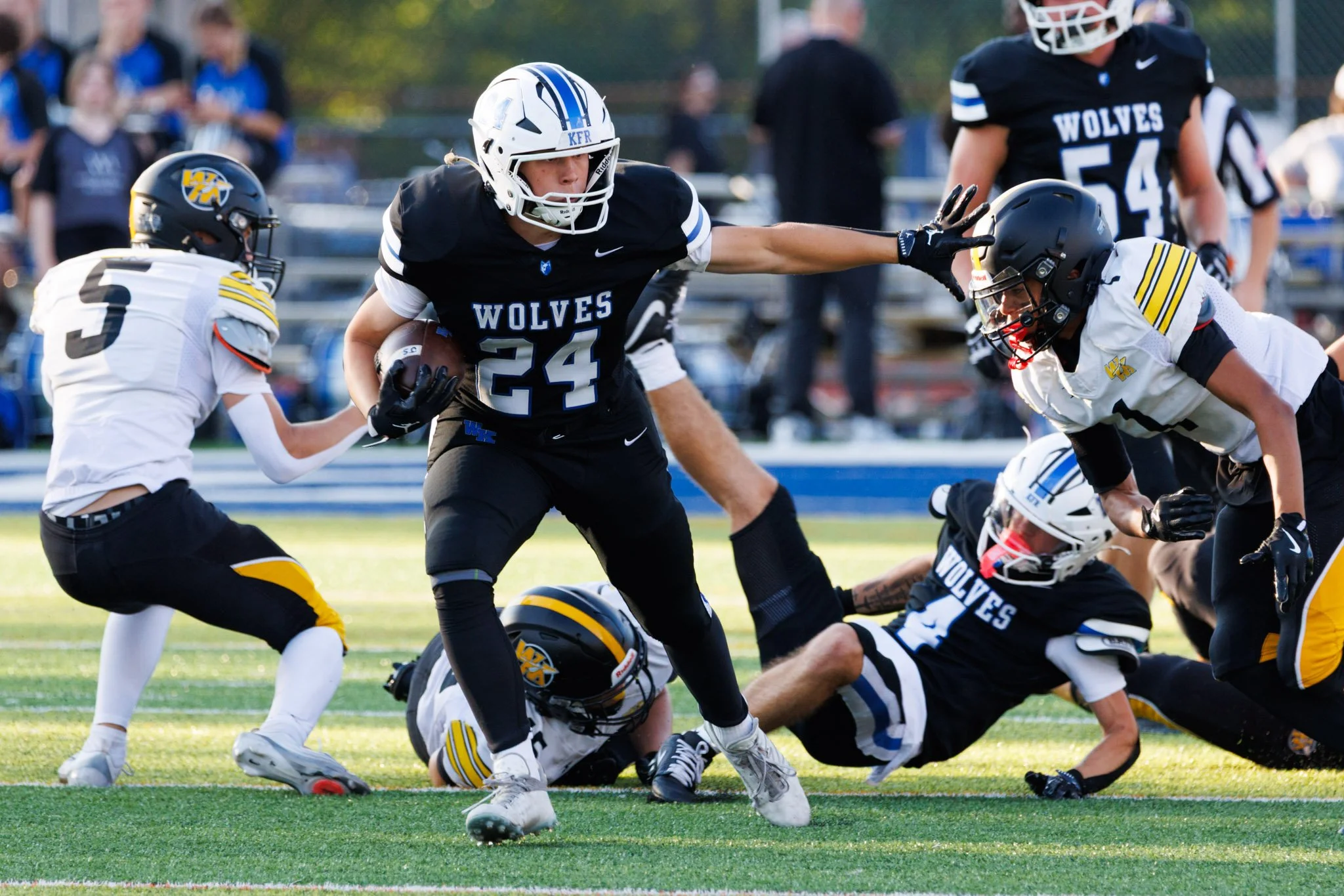 Running back breaking tackles with the stiff arm in a football game.