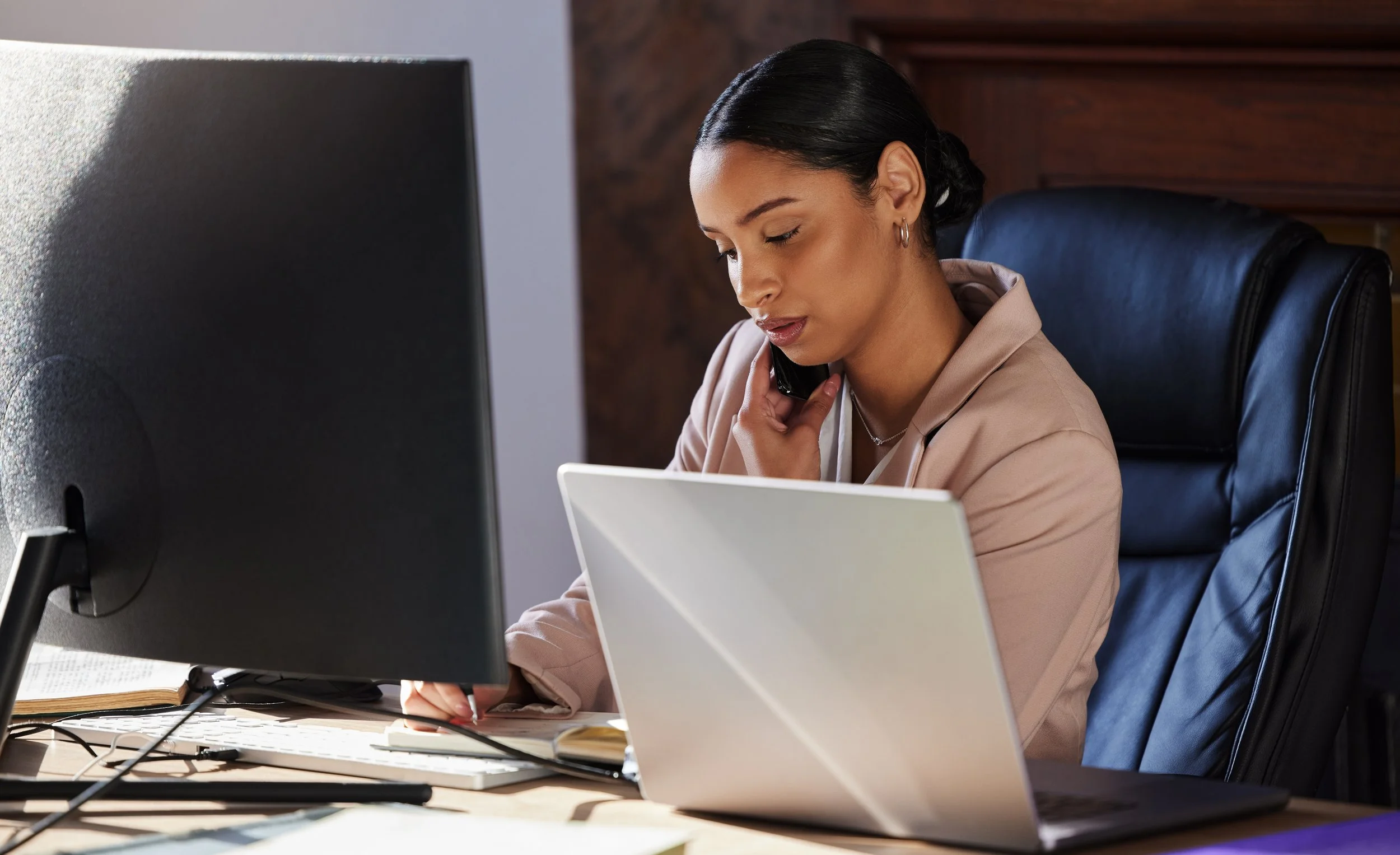 woman sitting at her desk working in front of computers and on the phone conducting business