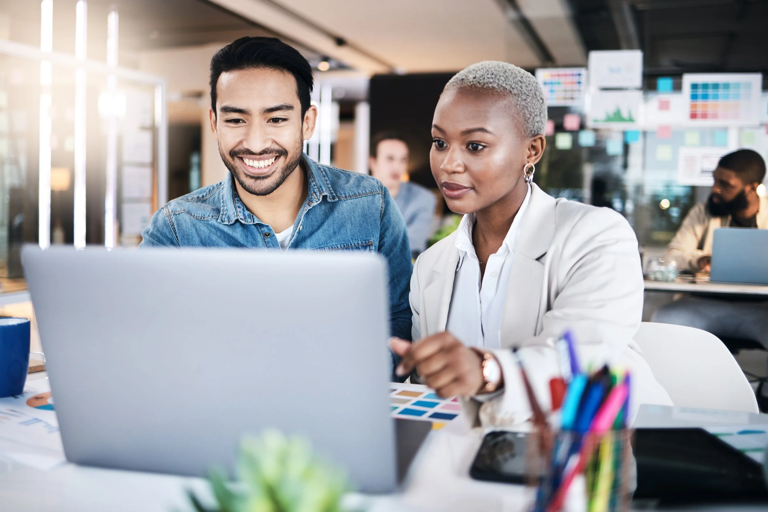 man on the left, woman on the right both smiling and looking at a computure making decisions