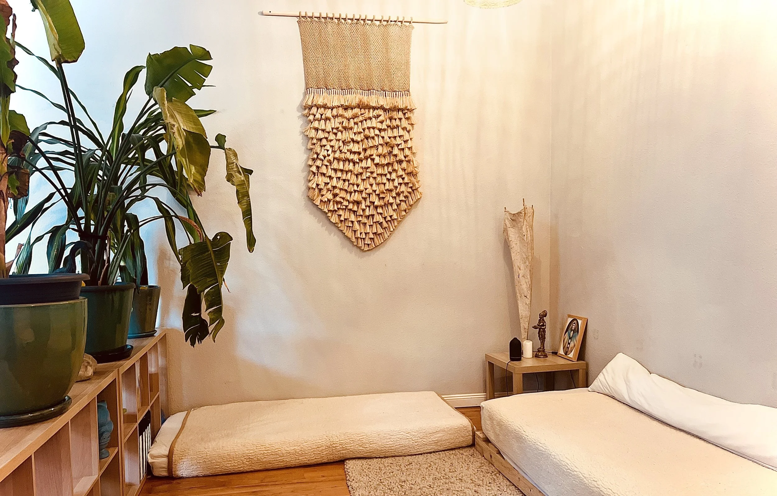 Ein Zimmer mit zwei Bodenkätzen, Pflanzen, einem Wandteppich und einigen Dekorationsgegenständen.