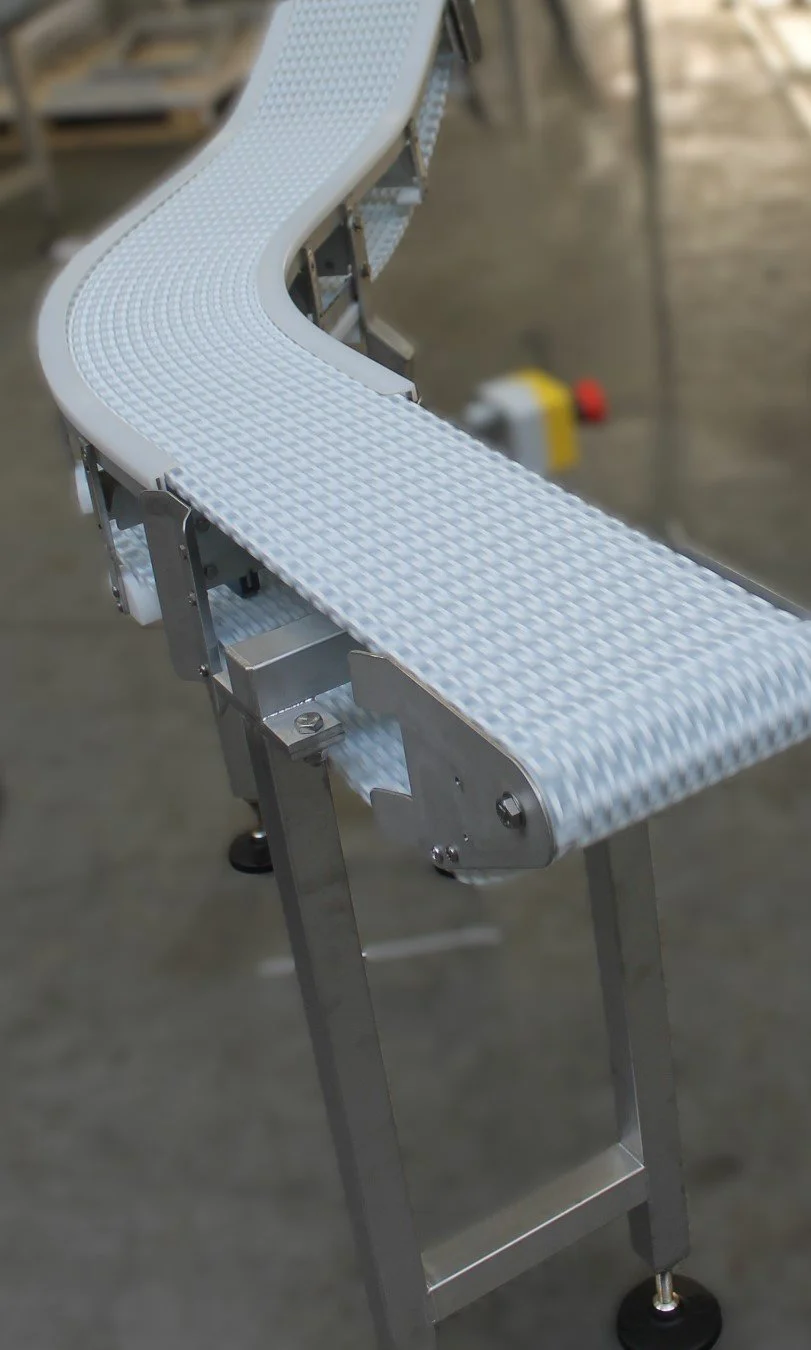 Close-up of a white conveyor belt with a textured surface, part of an industrial conveyor system in a warehouse or factory setting.