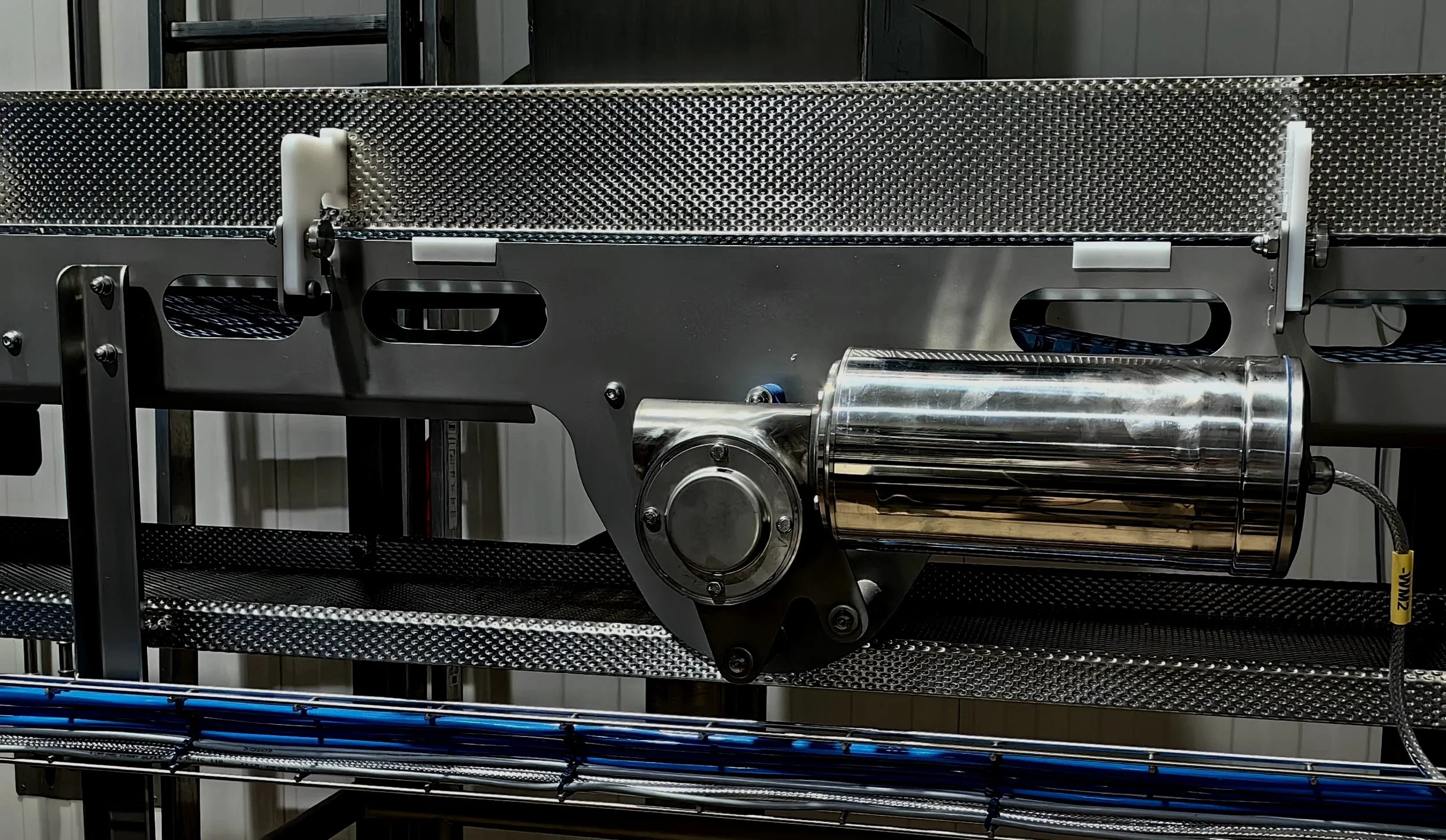 3D printer on a wooden table printing blue cylindrical objects.